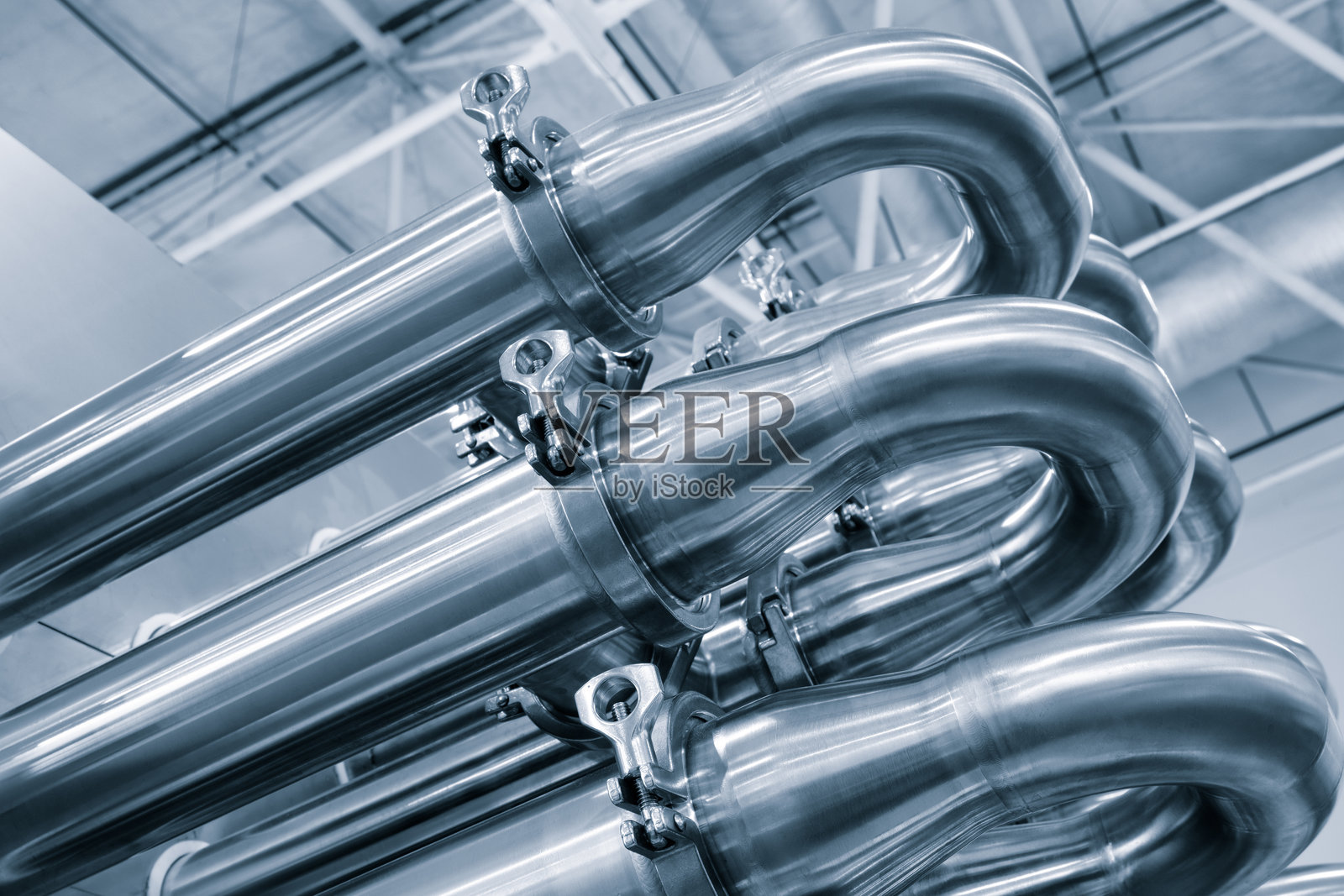 奶牛养殖场冷却器的散热器，配有一排带有银色饰边的不锈钢金属管道。管道相互连接，似乎是一个更大系统的一部分。照片摄影图片