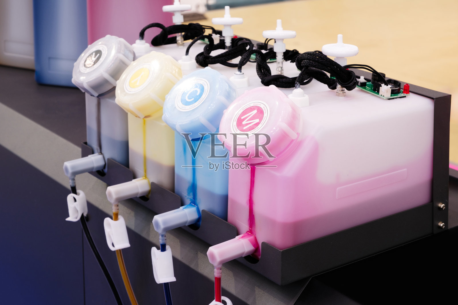 一排不同颜色的墨水罐，墨水罐连接到一台分装墨水的机器上。创意和拥有多种颜色创造独特色彩的重要性，喷墨打印机墨盒照片摄影图片