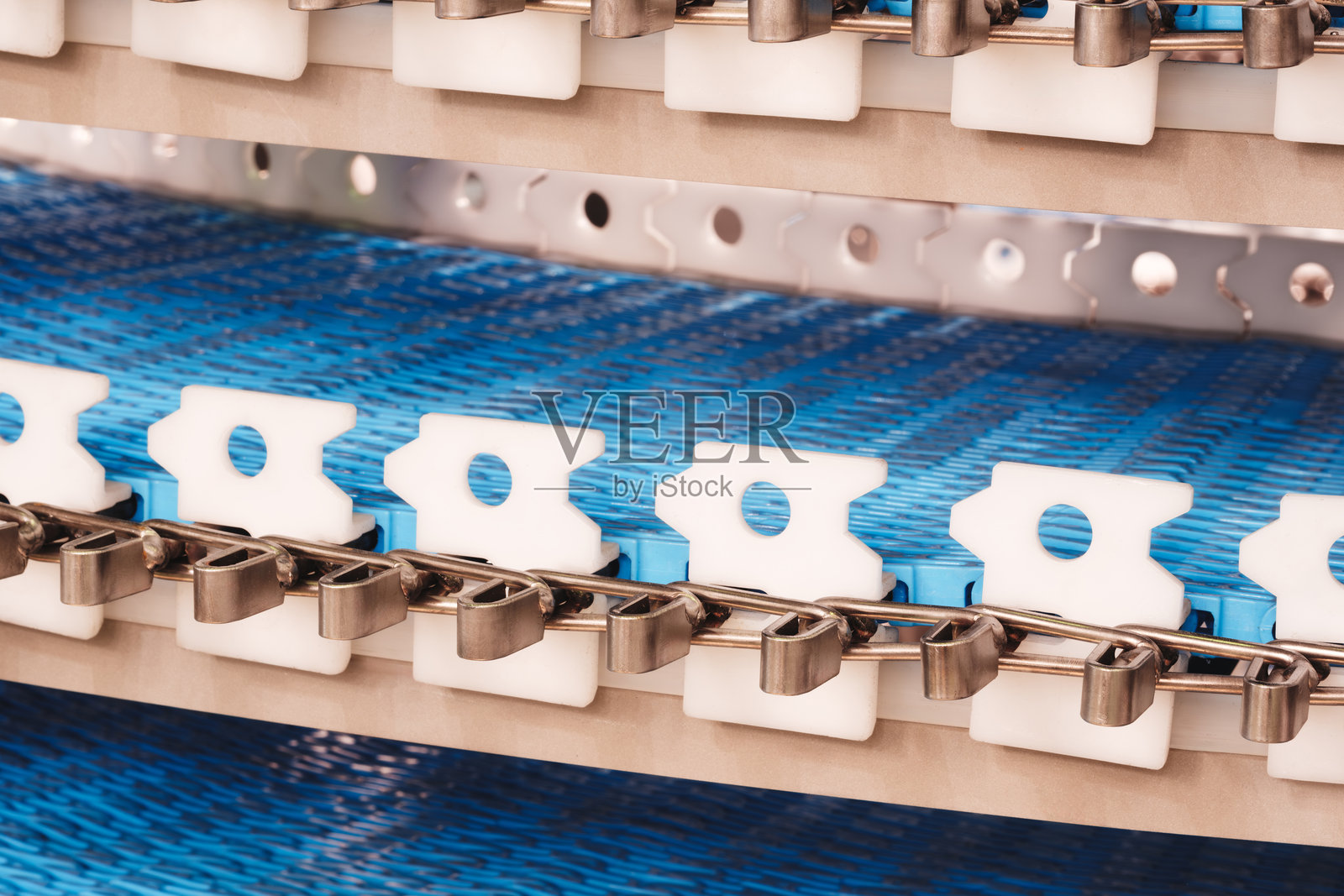 工厂里有一个蓝白色设计的传送带。该传送带由金属和塑料制成，用于将物品从一个地方运送到另一个地方。照片摄影图片