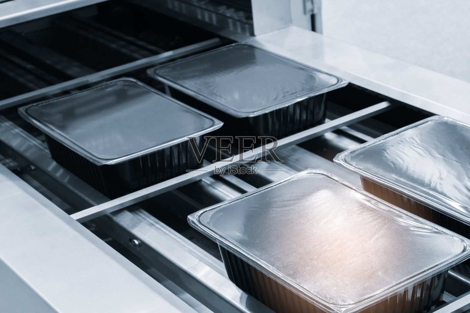 带灯光效果的自动聚乙烯塑料袋生产机。在浅蓝色场景中，塑料袋生产机滚筒的特写。产品包装概念照片摄影图片