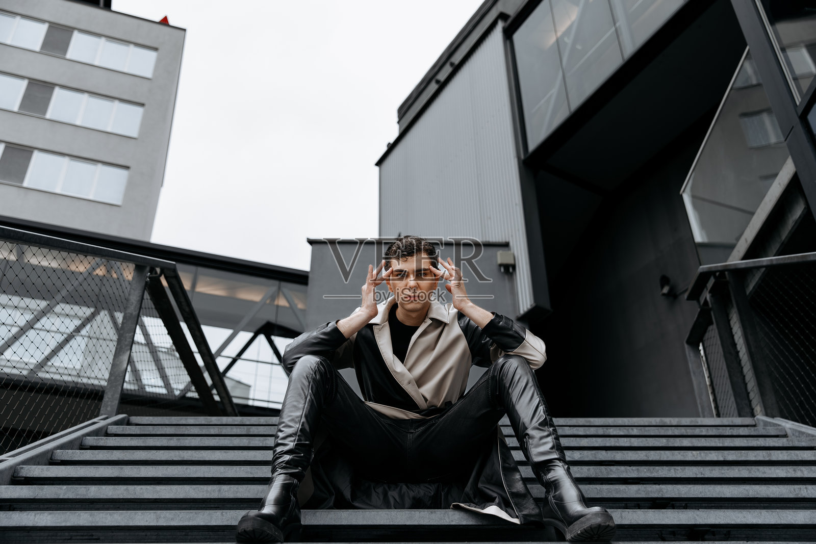 穿着都市风格服装的年轻高加索男性坐在工业风格的楼梯上照片摄影图片