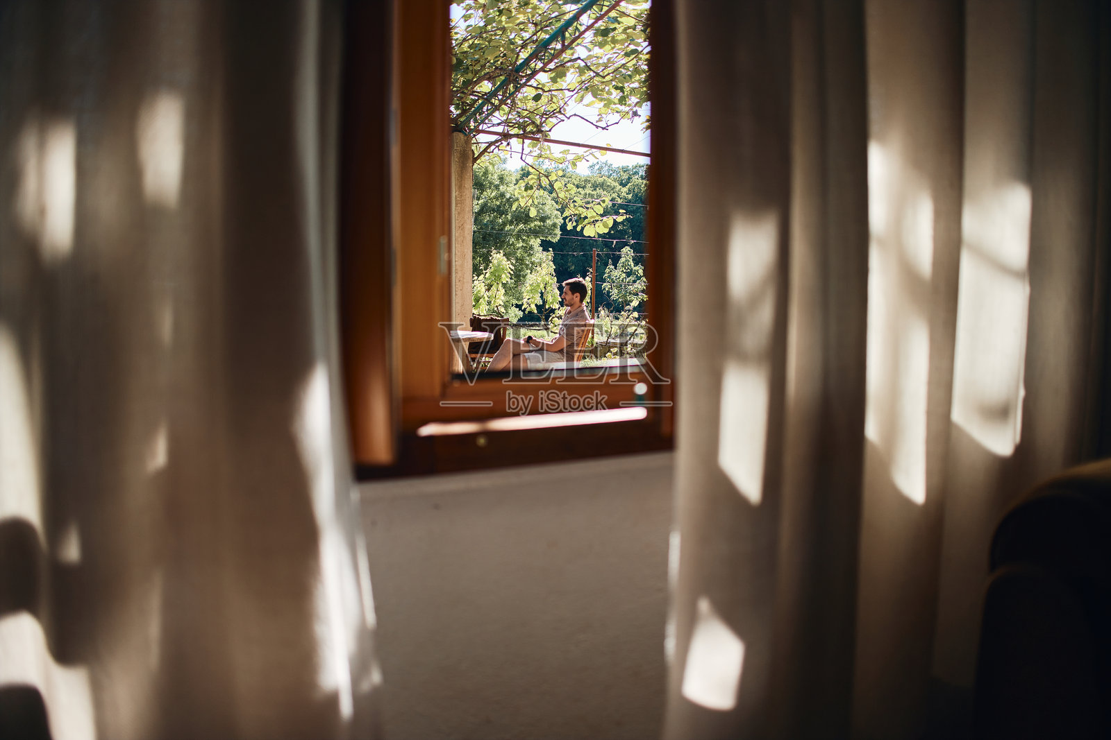 男人在阳台上放松，眺望阳光明媚的自然景色照片摄影图片