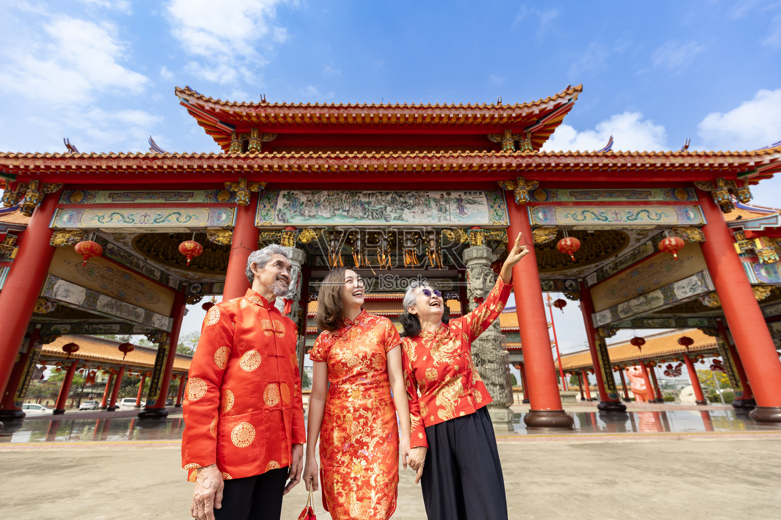 亚洲女性与她的年迈父母身着红色旗袍，在农历新年期间参观中国佛教寺庙，体验传统文化照片摄影图片