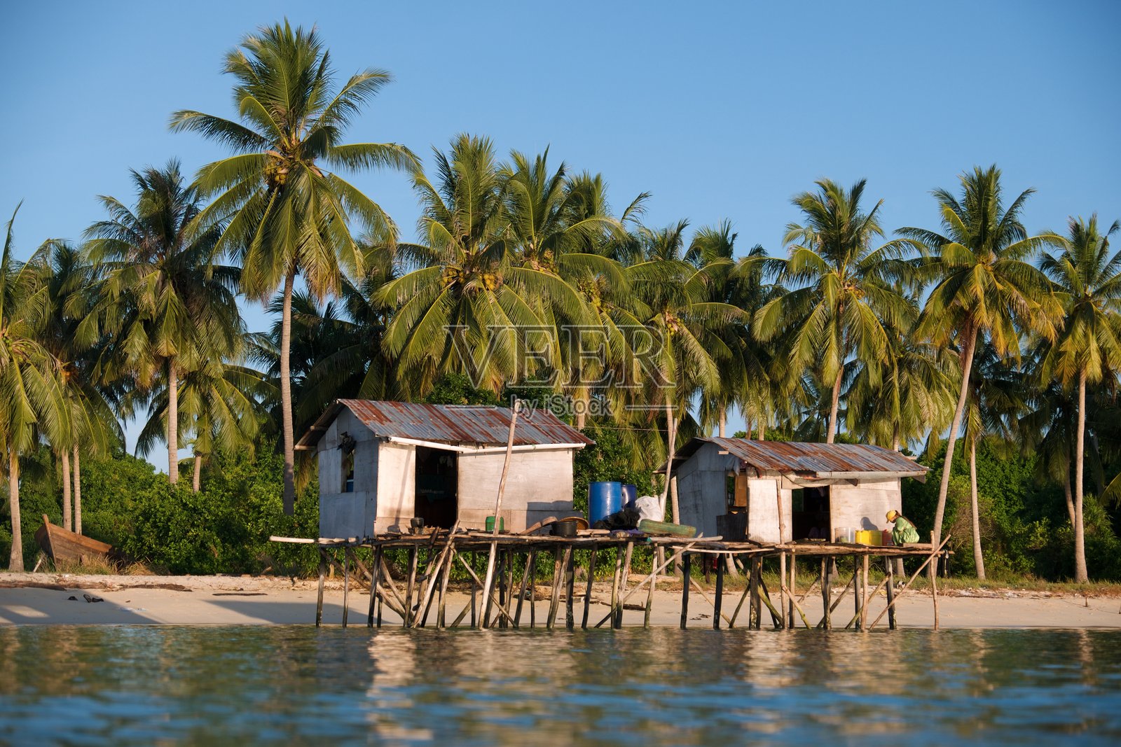 热带村庄中反映经济不平等的海岸高跷房屋照片摄影图片