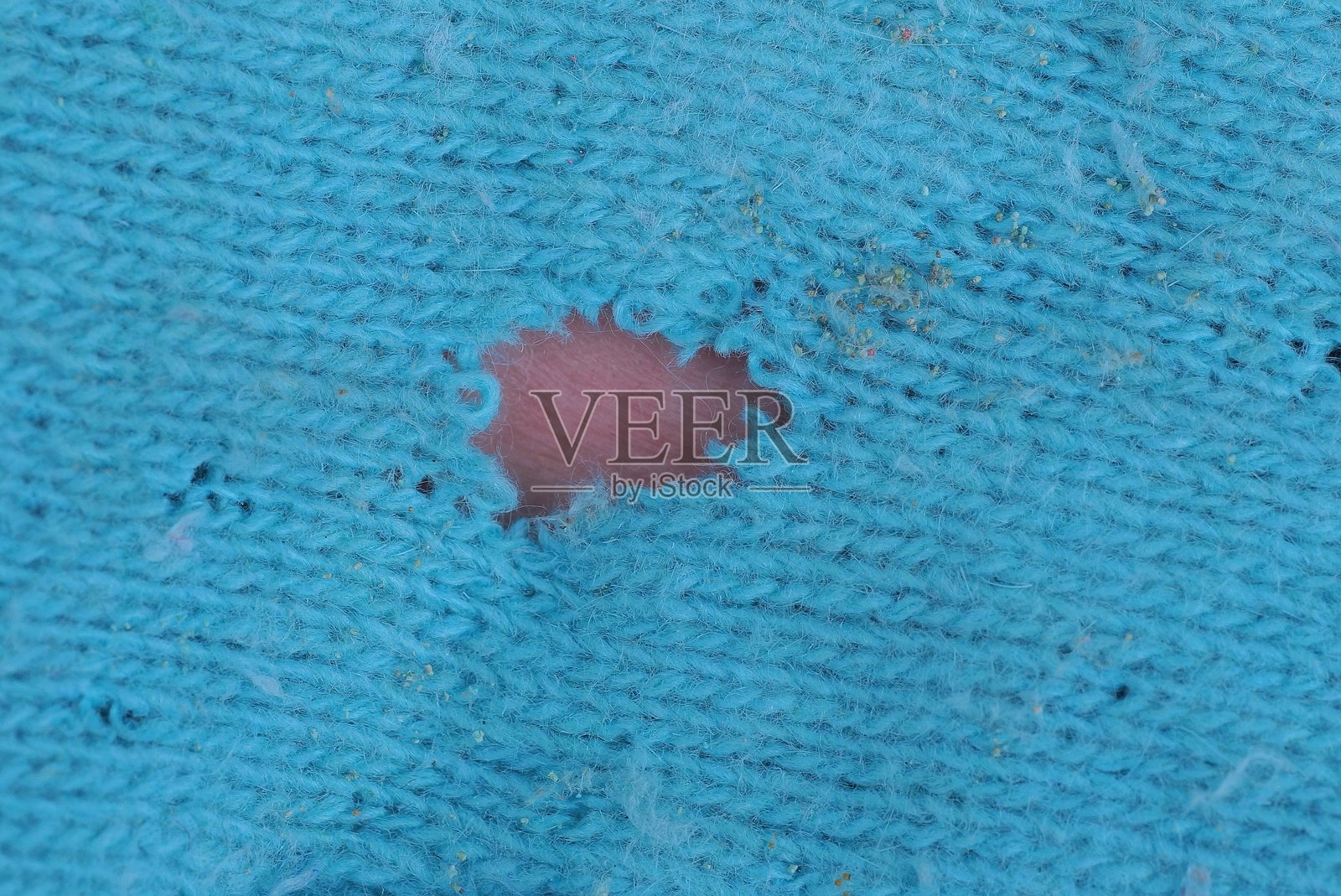 蓝色纹理的羊毛撕裂织物，带有一个棕色破洞照片摄影图片