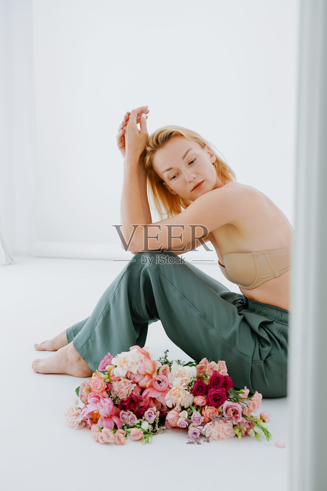 工作室里，年轻美丽的女孩和鲜花。自信的女人与鲜花。手持牡丹的女性。照片摄影图片