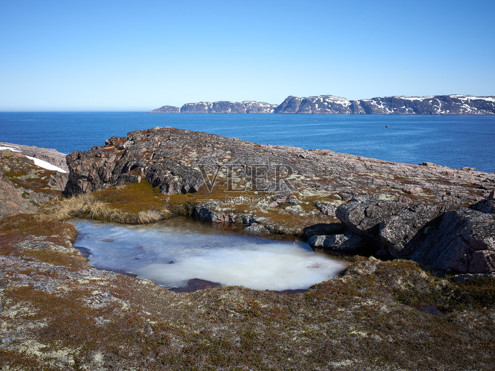 蓝色海水，洁净天空，寒冷巴伦支海岩石海岸边北方的岩石花岗岩海岸。照片摄影图片