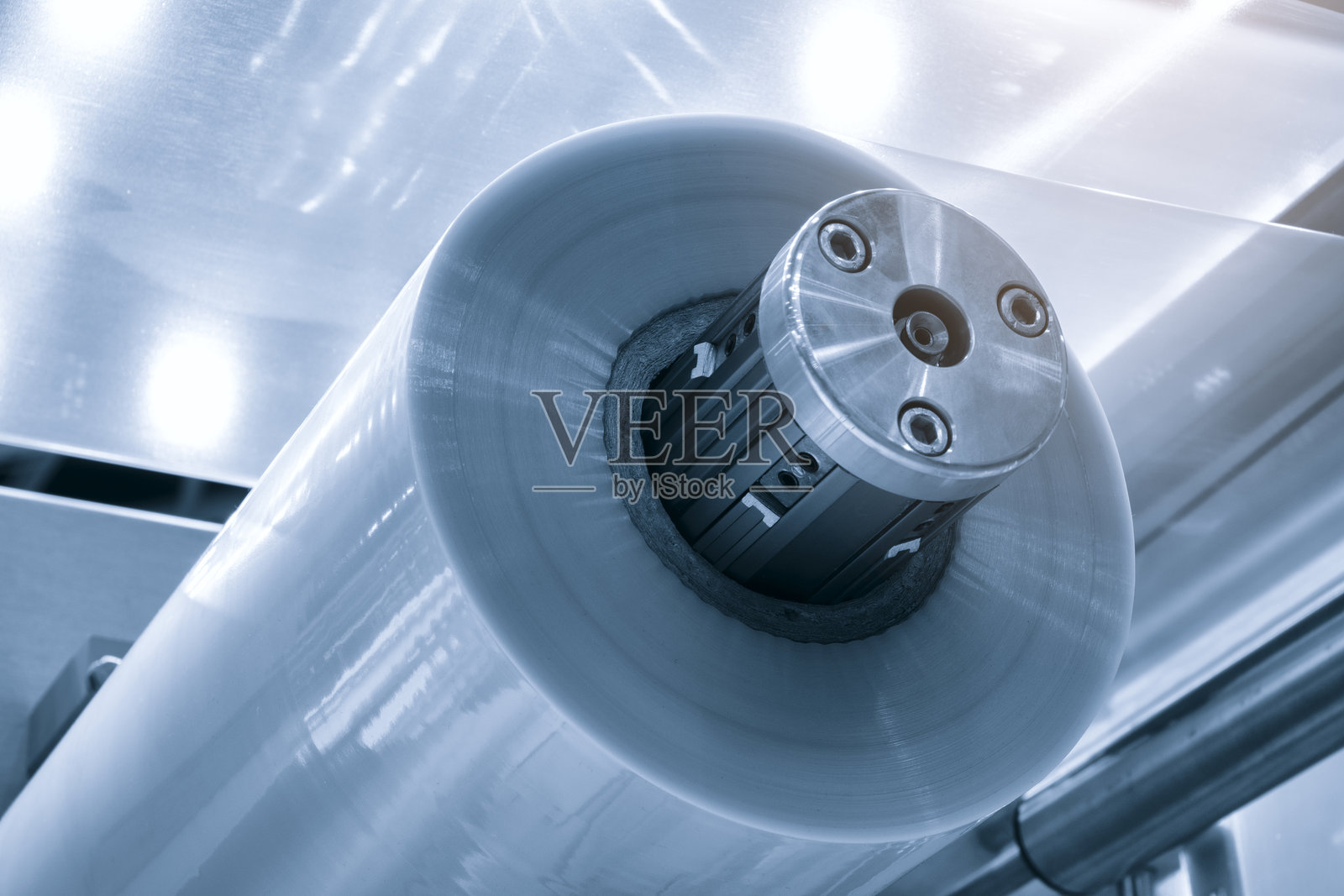 带灯效的自动聚乙烯塑料袋生产机。在浅蓝色场景中，塑料袋生产机滚筒的特写。产品包装理念。照片摄影图片