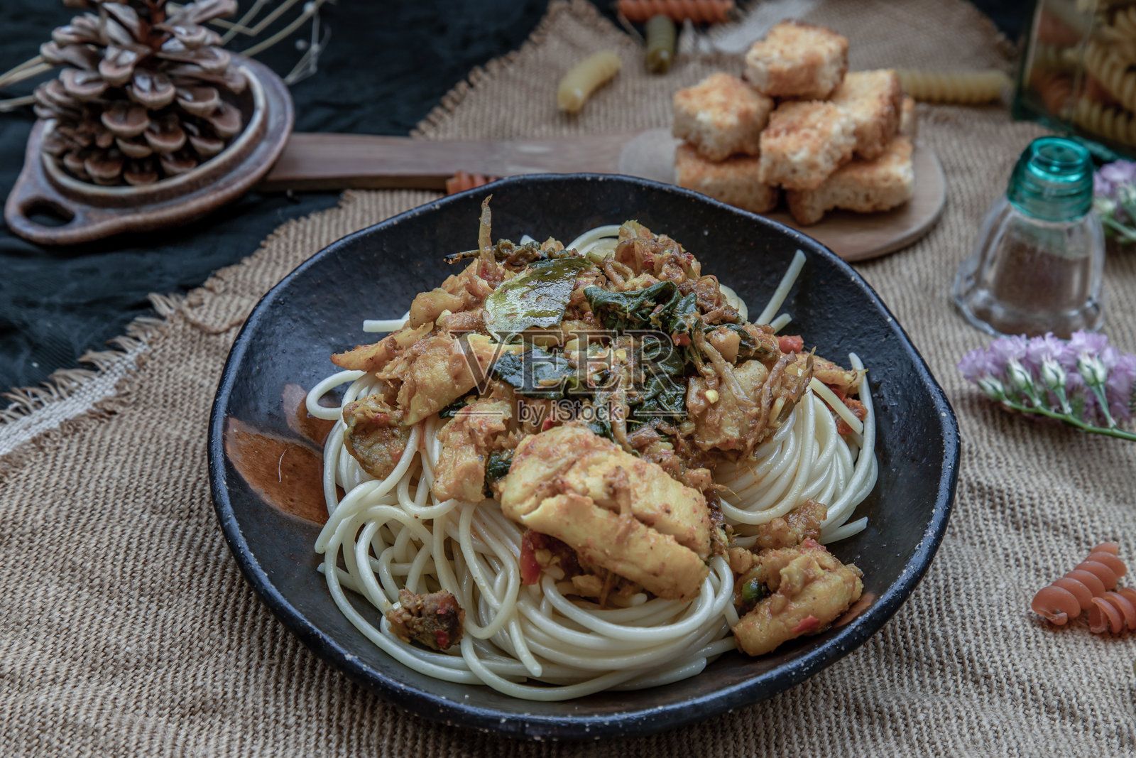 棕色盘子里的意大利面，上面铺着香辣炒鲷鱼片，配脆黄油吐司。照片摄影图片