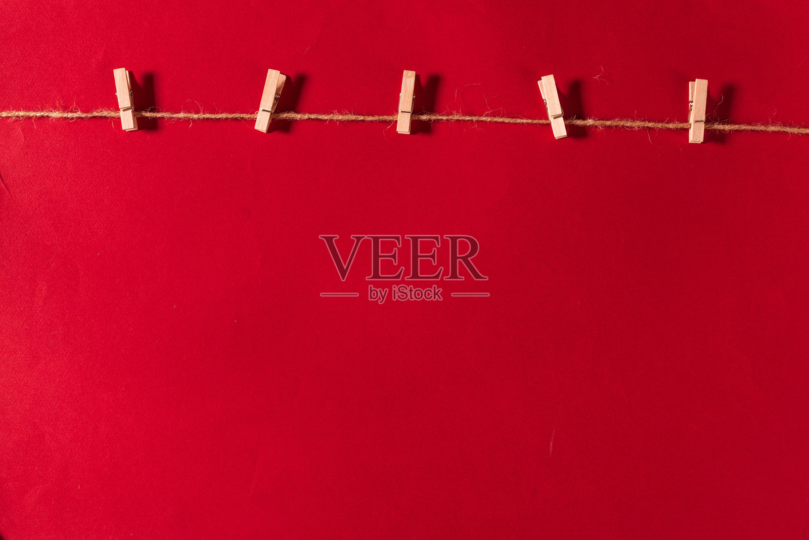 室内布置的晾衣绳上挂着晾衣夹，背景为红色照片摄影图片