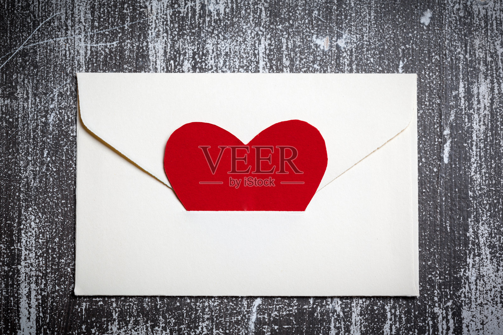 红心从信封里探出，放在木质表面上照片摄影图片