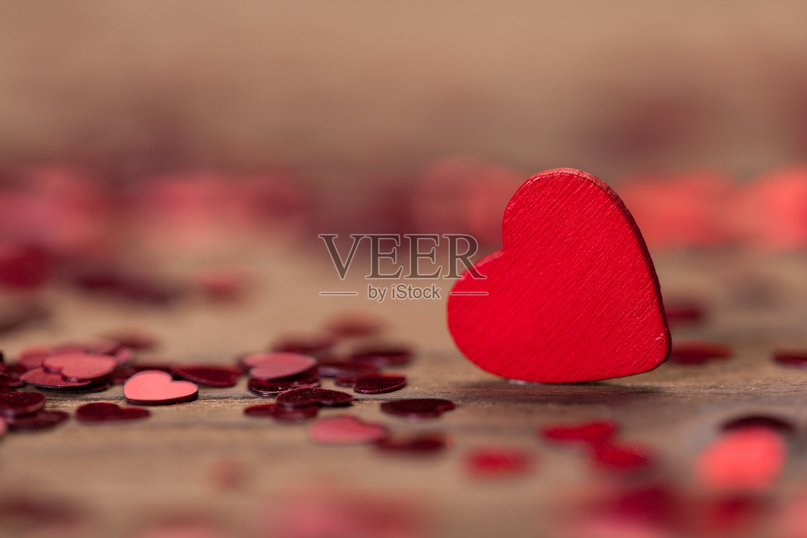 木质表面上被小爱心纸屑包围的红色爱心装饰照片摄影图片