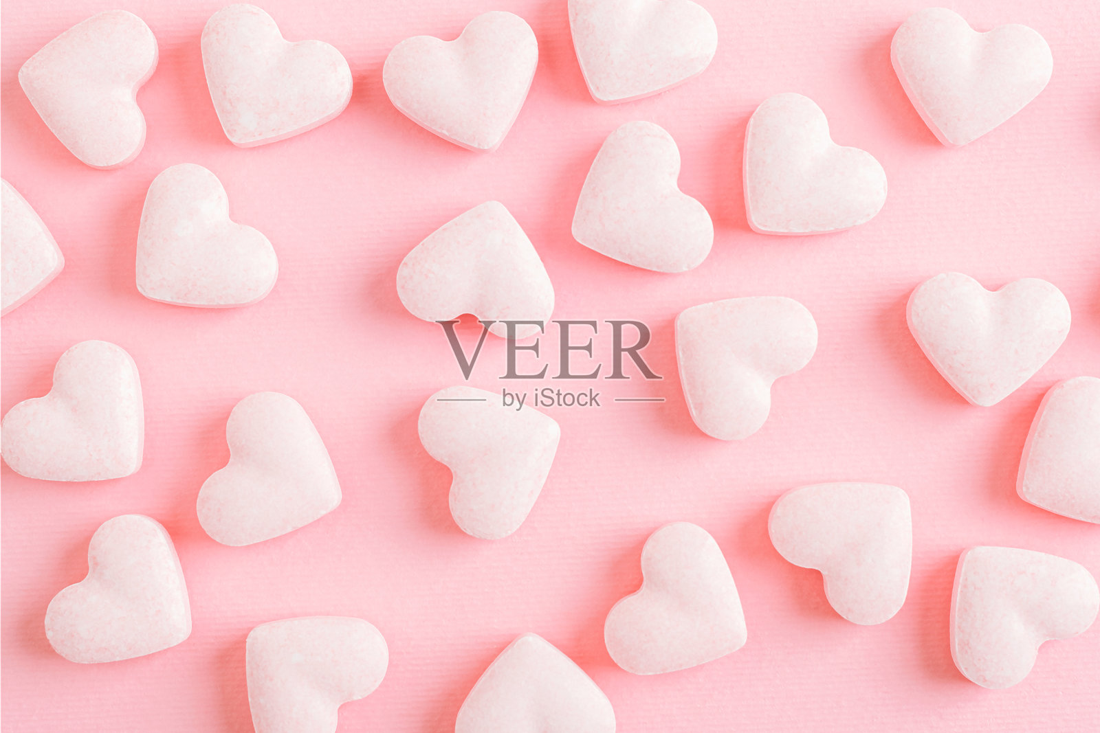 粉色糖果呈心形，背景为粉色。充满爱意的创意节日概念，情人节照片摄影图片