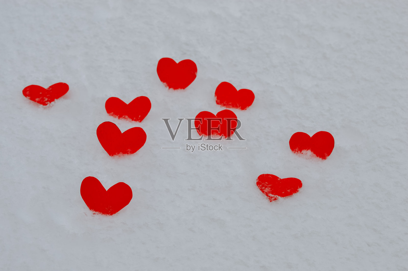 散落在雪地上的红色纸心，情人节浪漫背景，适用于爱情主题设计、贺卡、节日广告、社交媒体、婚礼和约会推广照片摄影图片