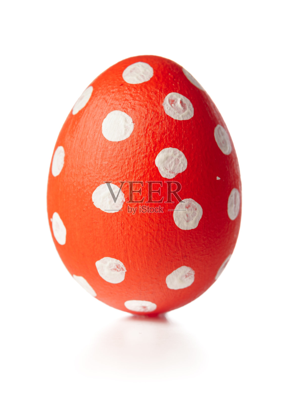 在春季庆祝活动中，一个带有白色斑点的亮红色复活节彩蛋放在白色背景上照片摄影图片