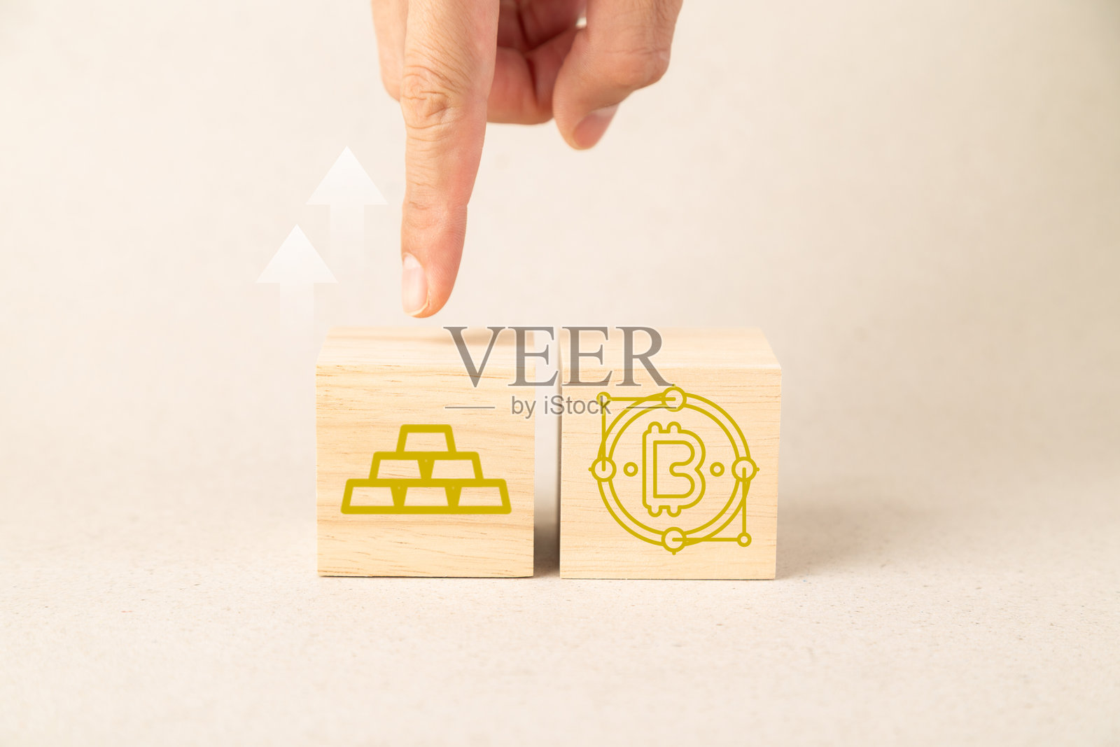 一只手指向木块，木块上印有金条和比特币图标，并带有向上的箭头，象征着财务增长、投资策略以及在数字资产和传统黄金之间的选择照片摄影图片