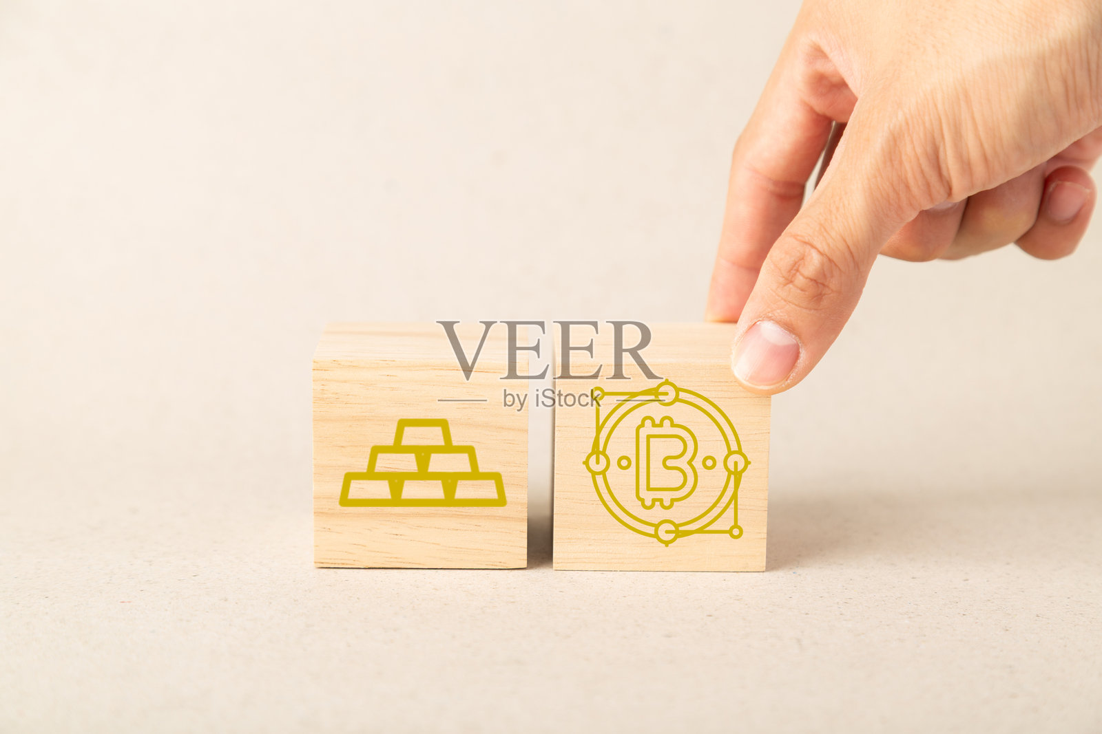 一只手将带有比特币图标的木块放在金条图标木块旁边，代表金融多元化、数字货币与黄金之间的投资选择以及现代资产管理照片摄影图片