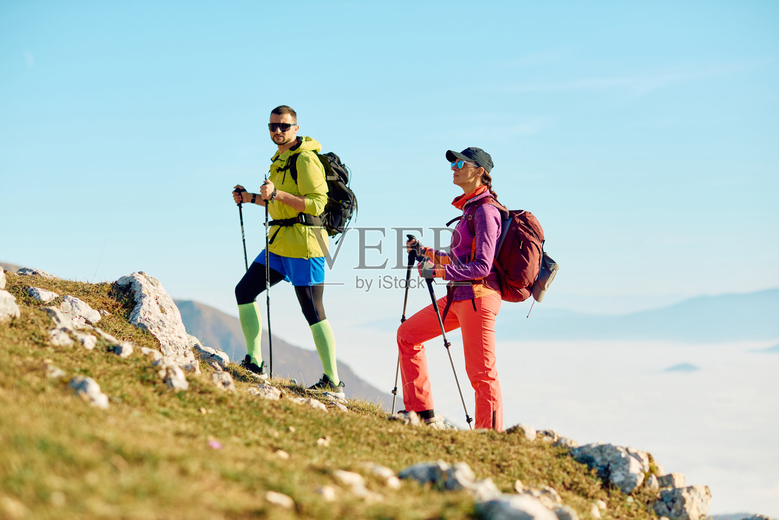 一对情侣在清晨时分，享受着在山间小径徒步的乐趣，天空晴朗，景色壮丽。照片摄影图片