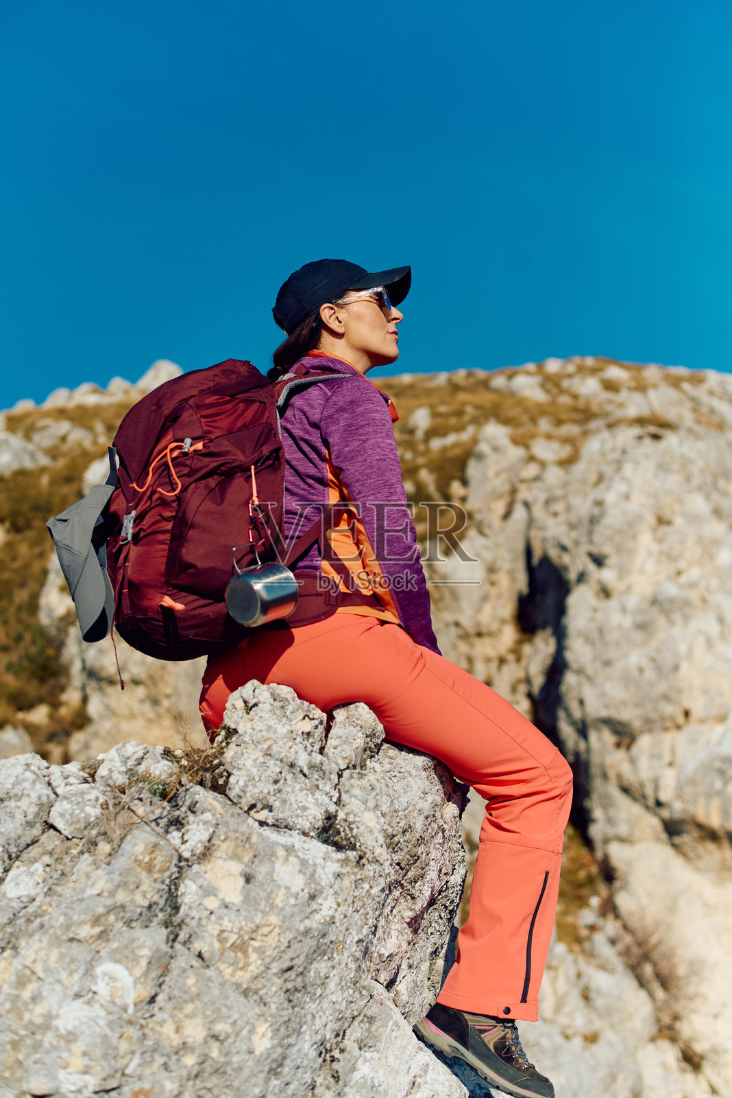 晴天时，徒步者背着背包在山间的岩石上休息，欣赏美景照片摄影图片