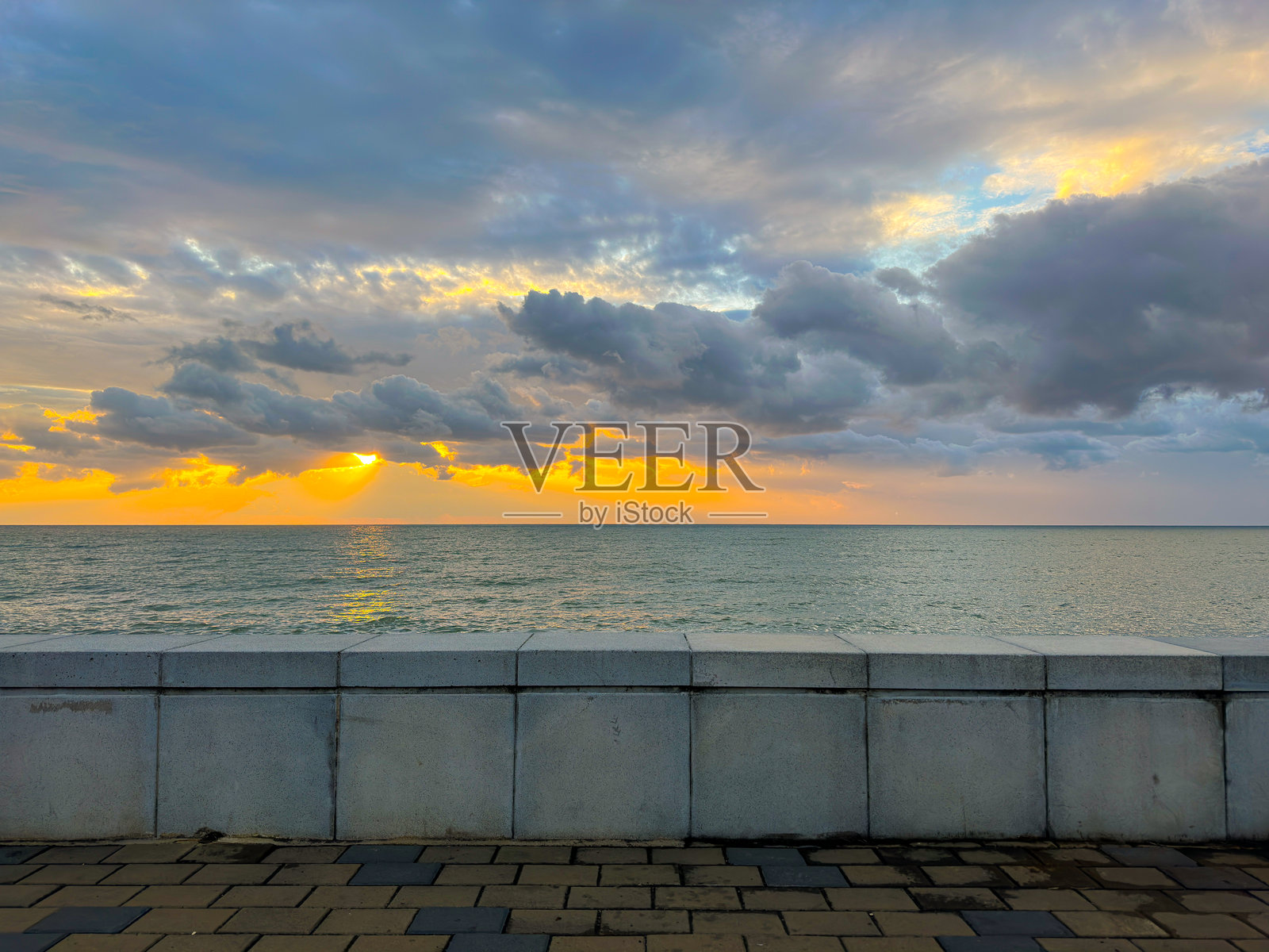 日落时分，混凝土海堤俯瞰平静的海面照片摄影图片