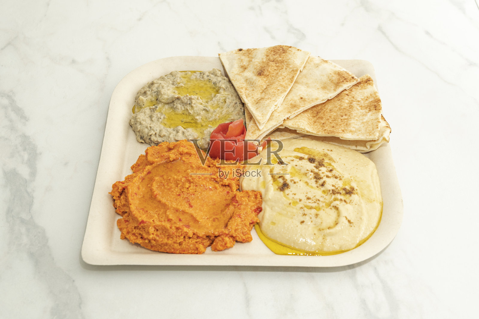 一碗丰盛的奶油状浅色鹰嘴豆泥，中央淋上特级初榨橄榄油，撒上甜椒粉。照片摄影图片