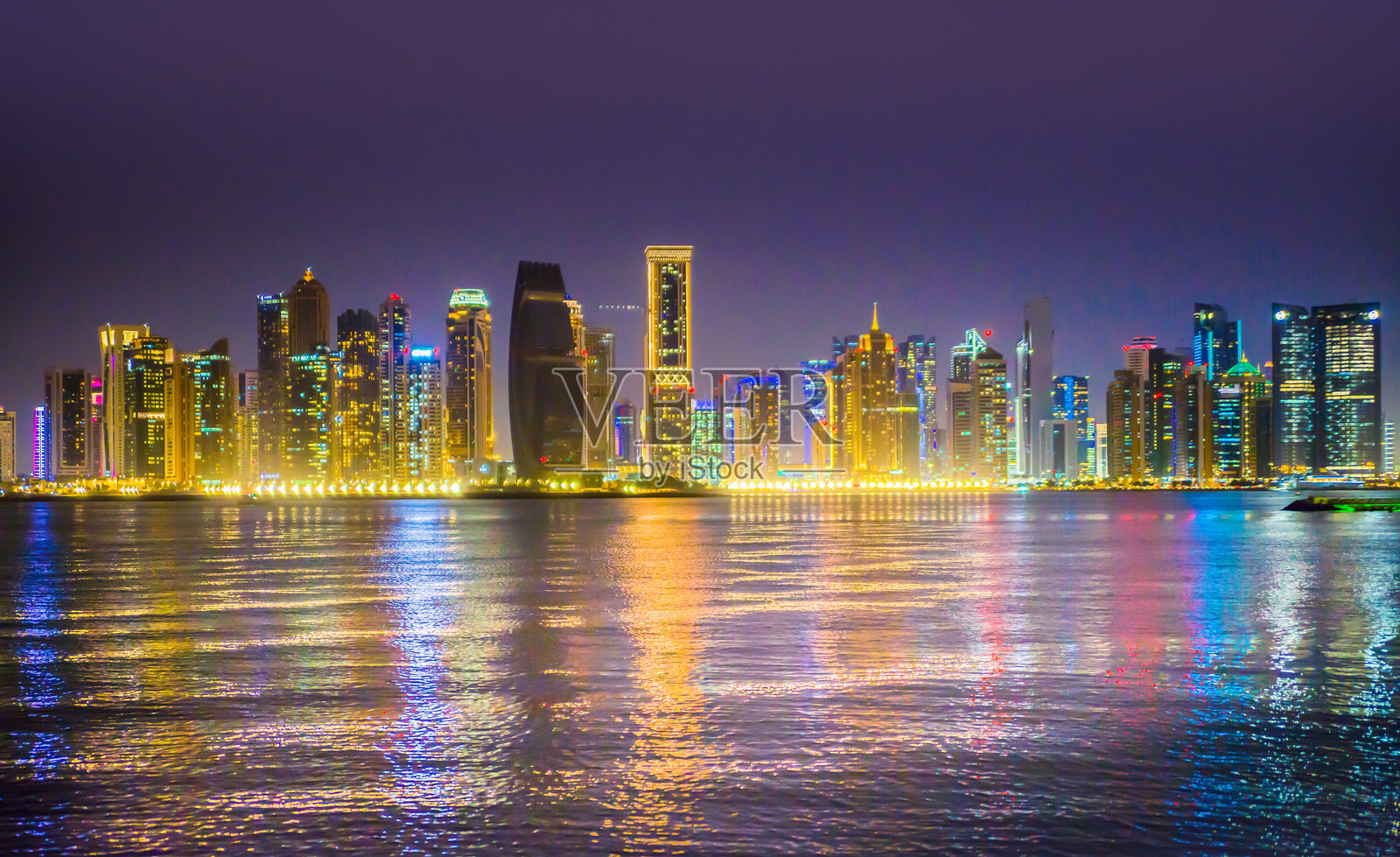 卡塔尔，多哈市美丽的夜景，金融区的摩天大楼及其在海湾水中的倒影。照片摄影图片