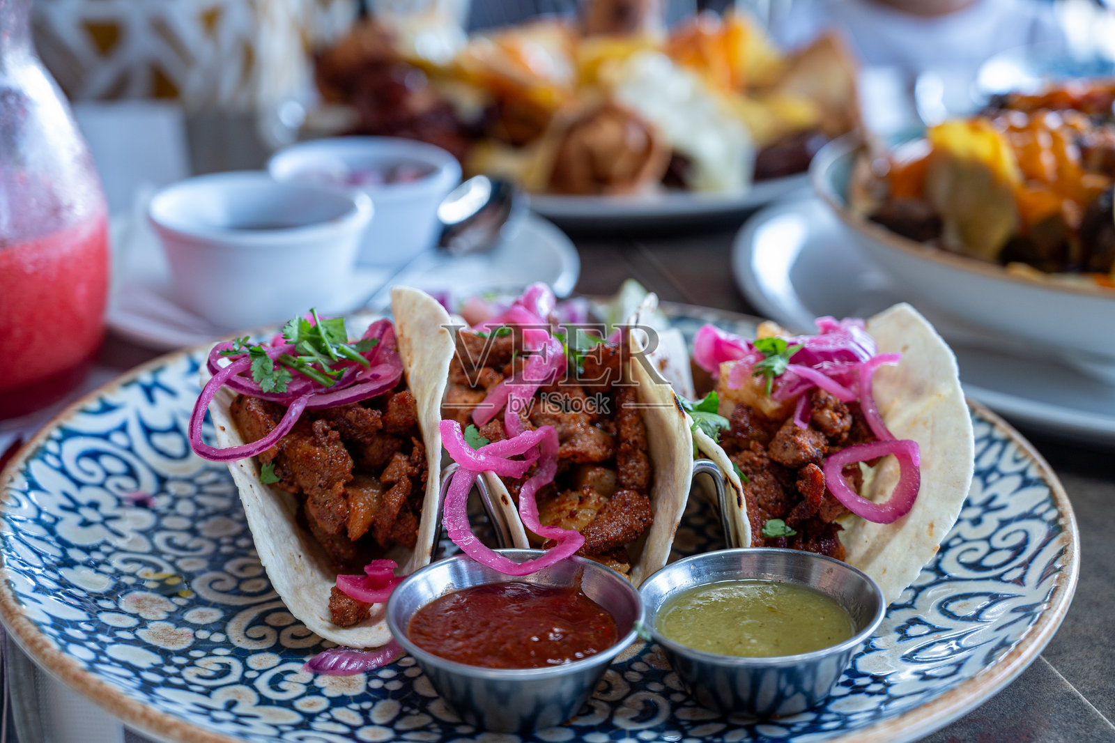 蓝盘子上放着三个玉米饼，上面有洋葱和绿色酱汁。照片摄影图片