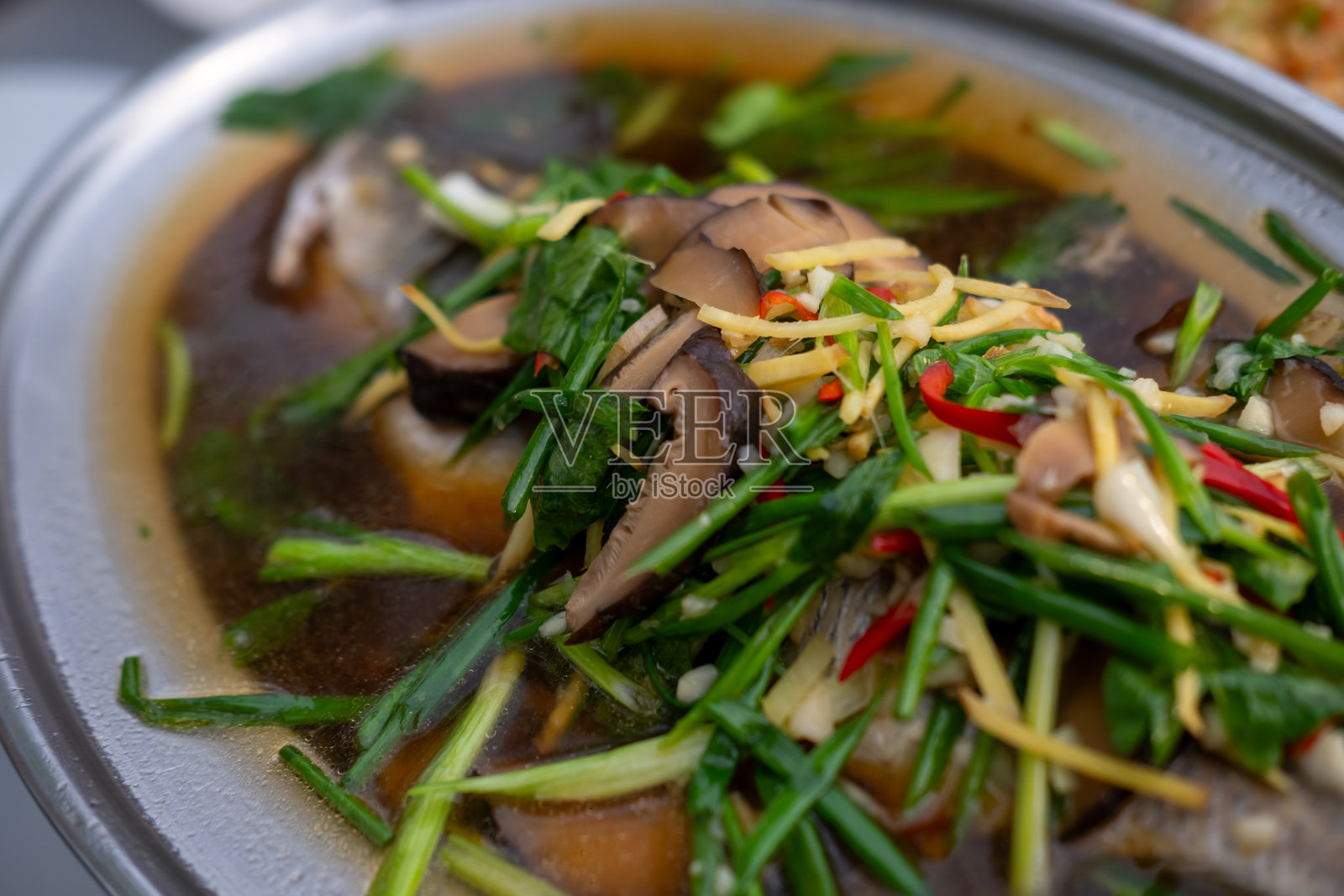 盘子上盛着的蒸海鲈鱼配酱油。泰式食物照片摄影图片