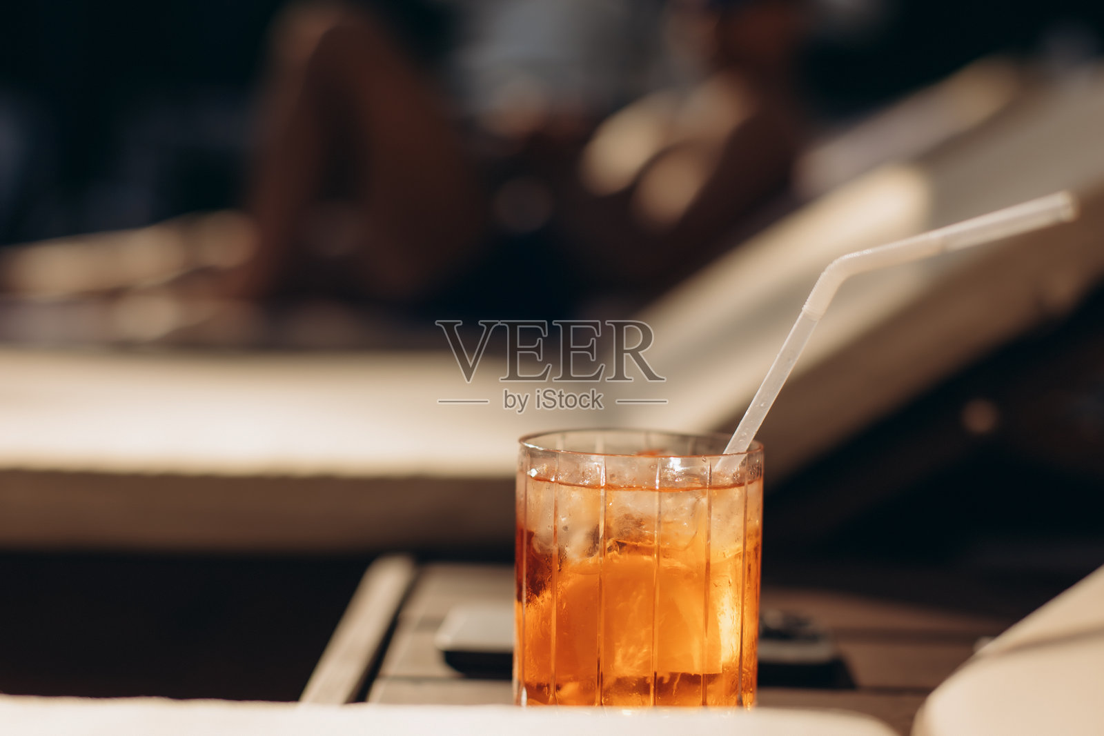 泳池边的躺椅旁桌上放着一杯清爽的橙味鸡尾酒照片摄影图片