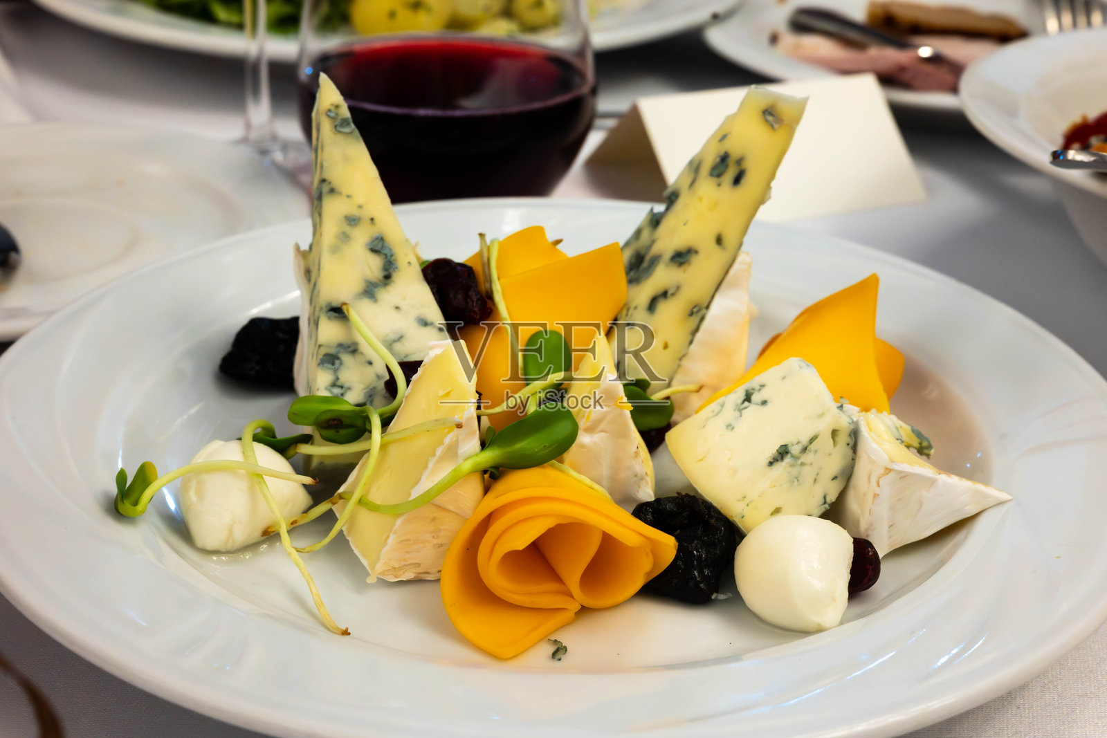 白色盘子里的各种奶酪，如切达奶酪、戈贡佐拉奶酪、马苏里拉奶酪和卡门贝尔奶酪照片摄影图片