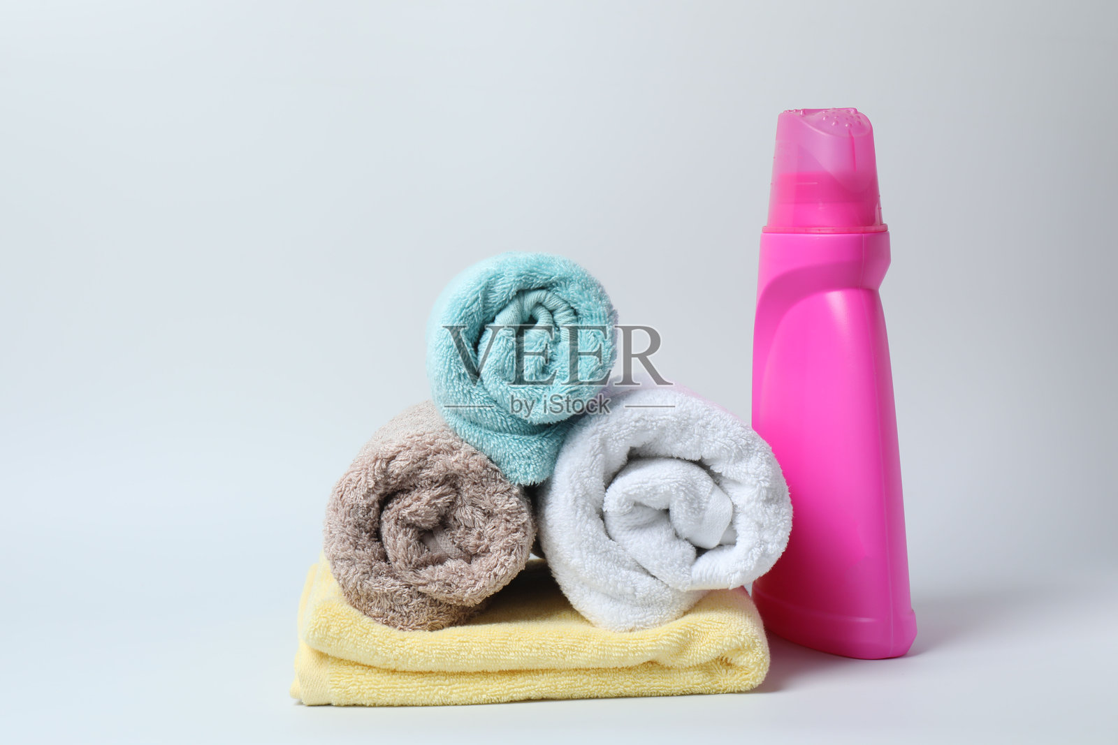 白色背景上的洗衣液瓶和一包干净的毛巾照片摄影图片