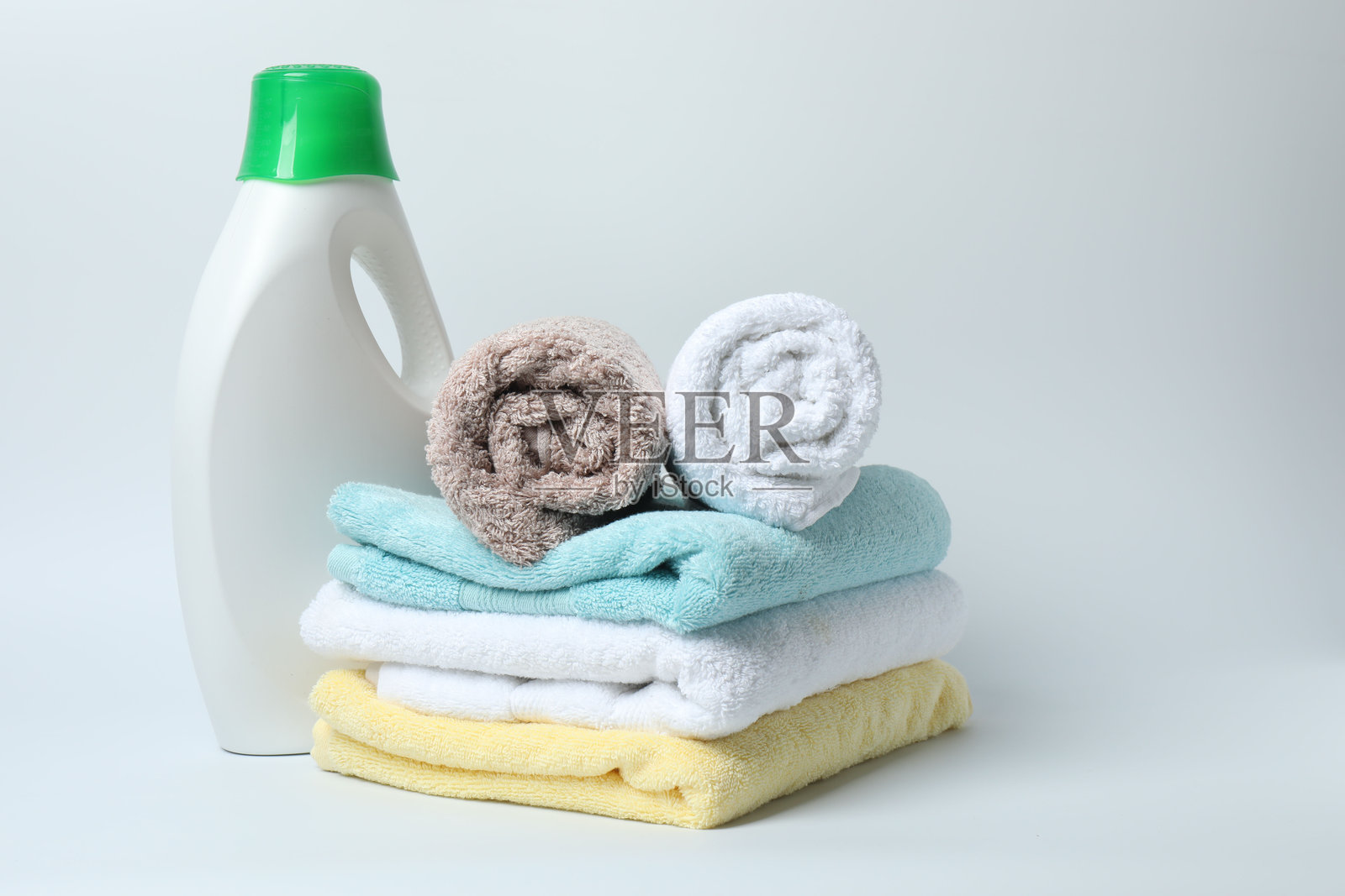 洗衣液瓶子和一包干净的毛巾，背景为白色照片摄影图片