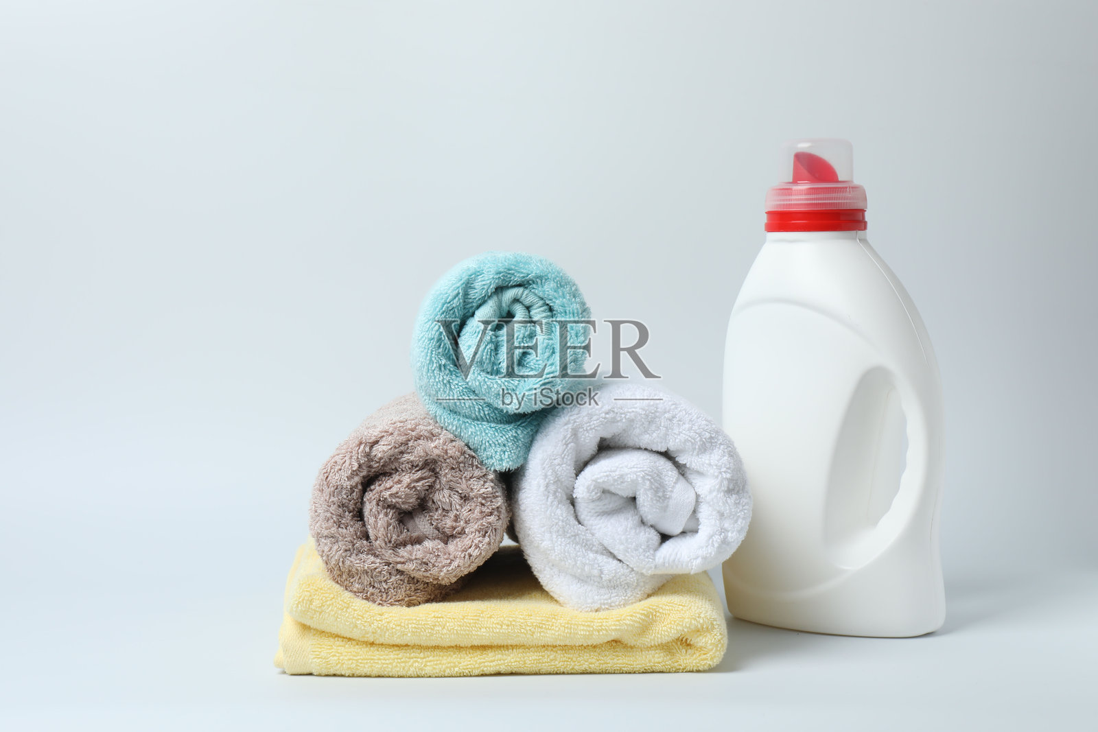 白色背景上的洗衣液瓶和一包干净的毛巾照片摄影图片