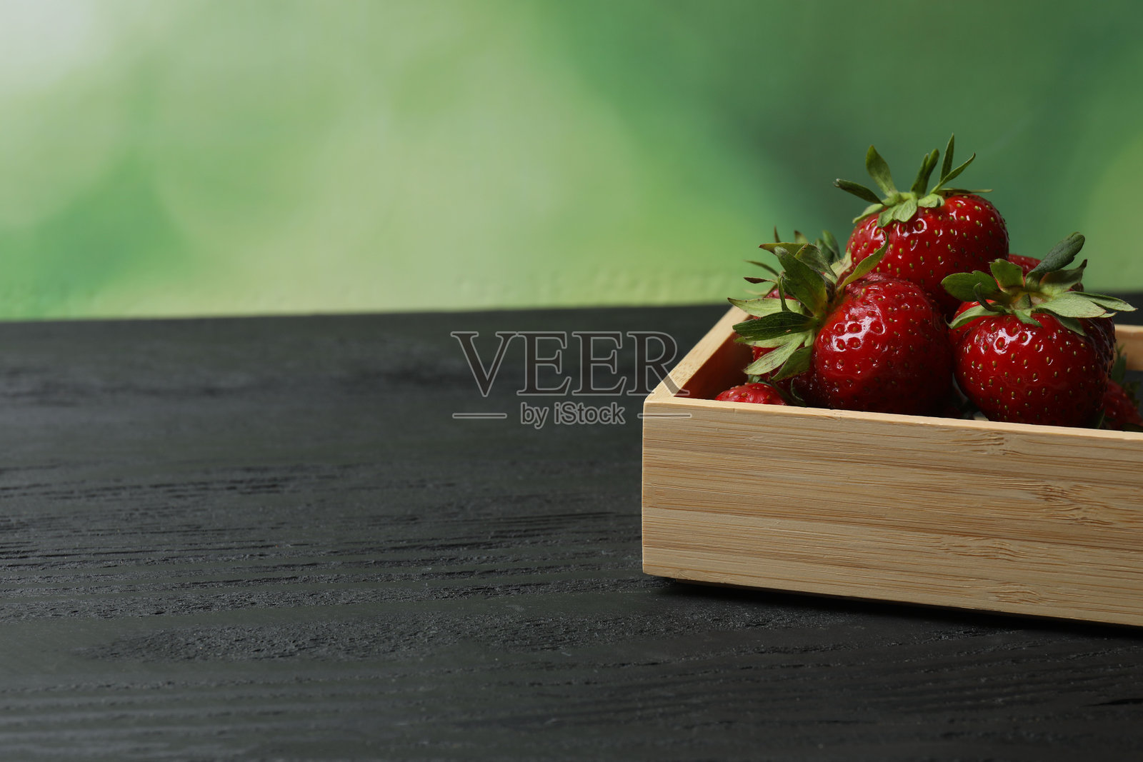 草莓放在木桌上的托盘里照片摄影图片