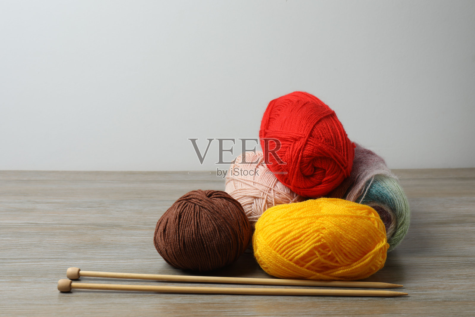 各种毛线和编织针放在木桌上，特写照片摄影图片