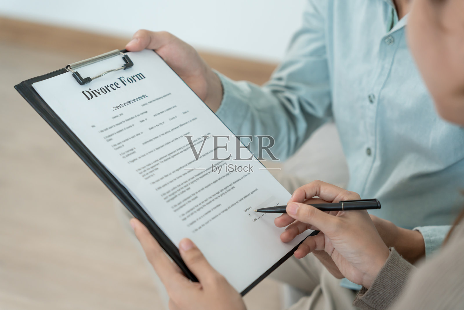 离婚。丈夫审阅并签署离婚协议。婚姻破裂后，夫妻二人绝望而失望。妻子在争吵冲突后伤心、沮丧、烦躁。不信任，感情问题照片摄影图片