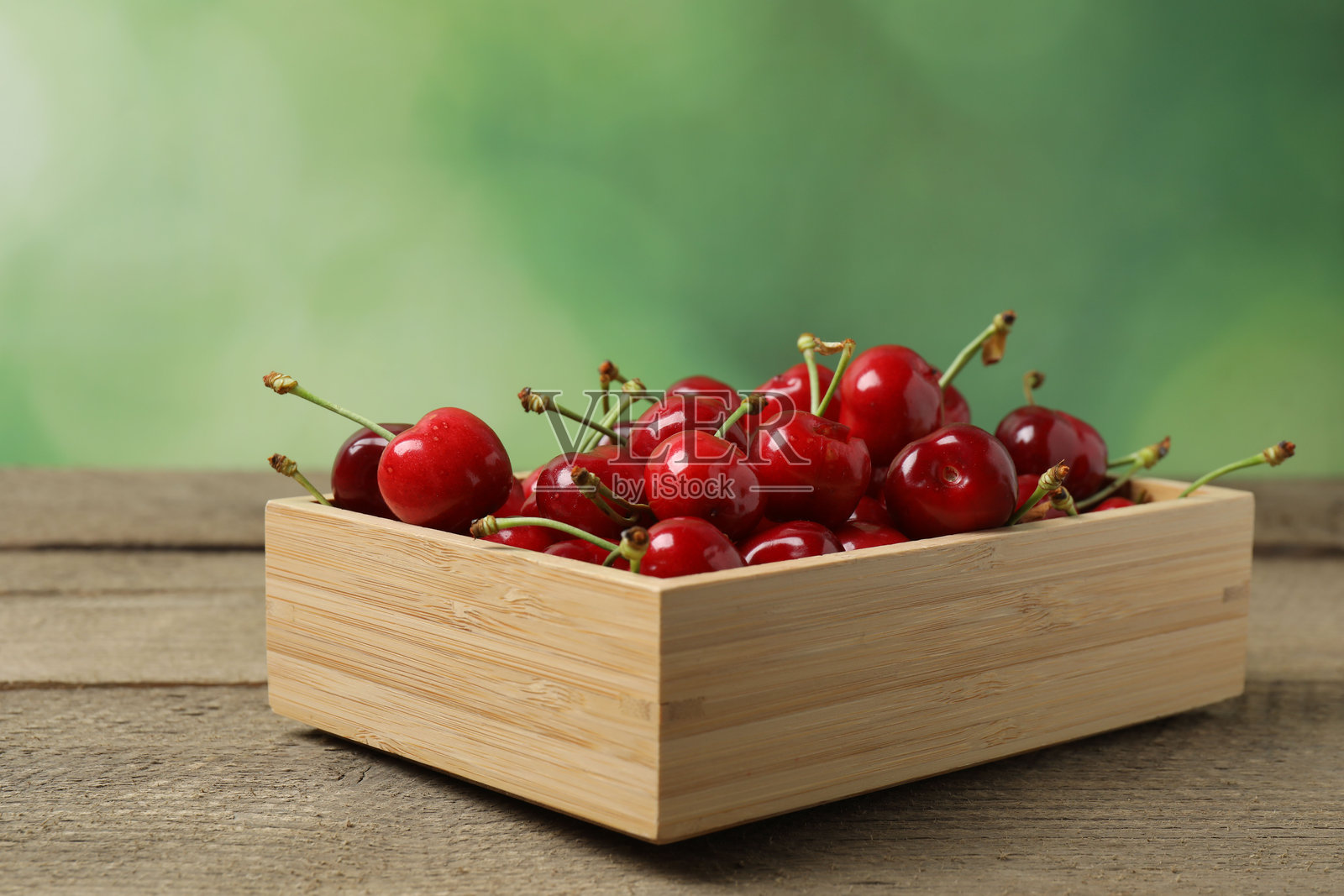 樱桃放在木桌上的托盘里照片摄影图片