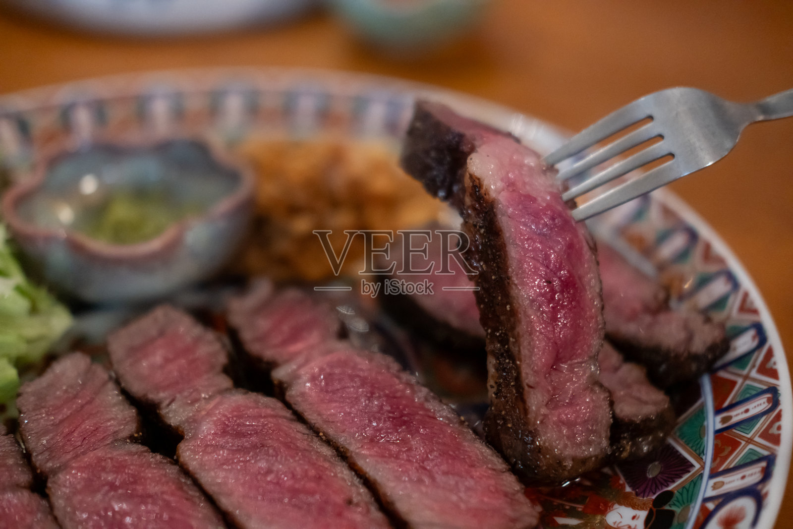 盘子上放着切片的五分熟肋眼牛排和蔬菜照片摄影图片