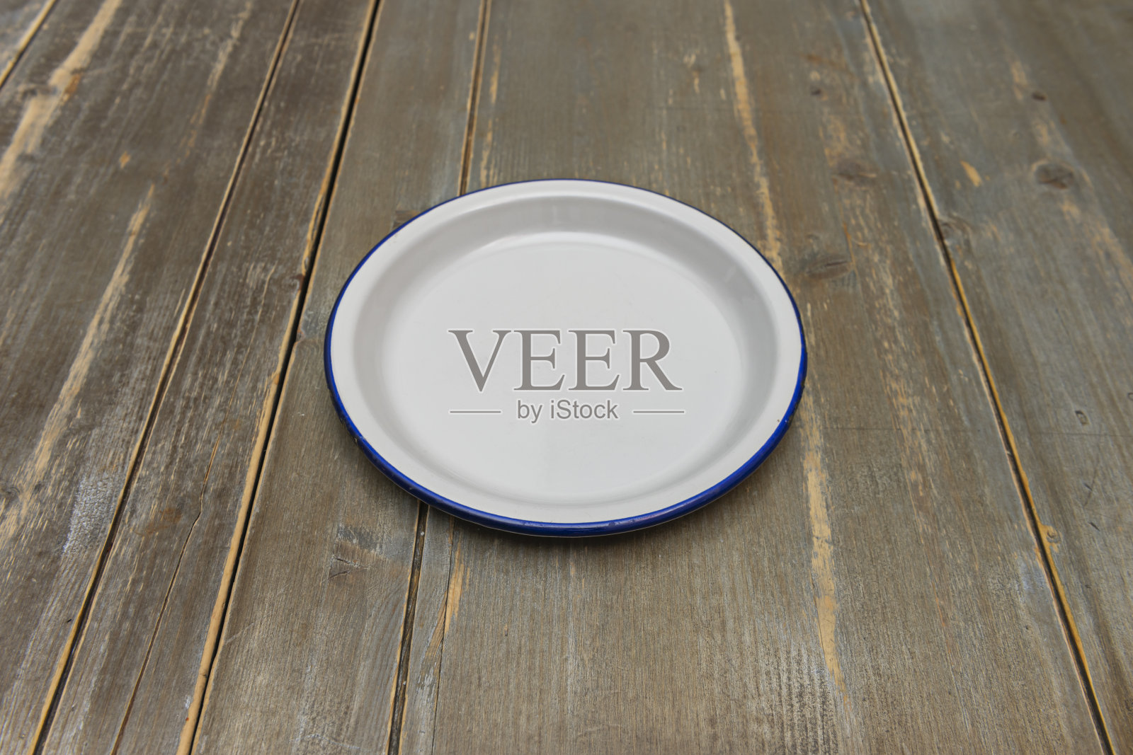 木桌上的金属盘，带有珐琅蓝边框照片摄影图片