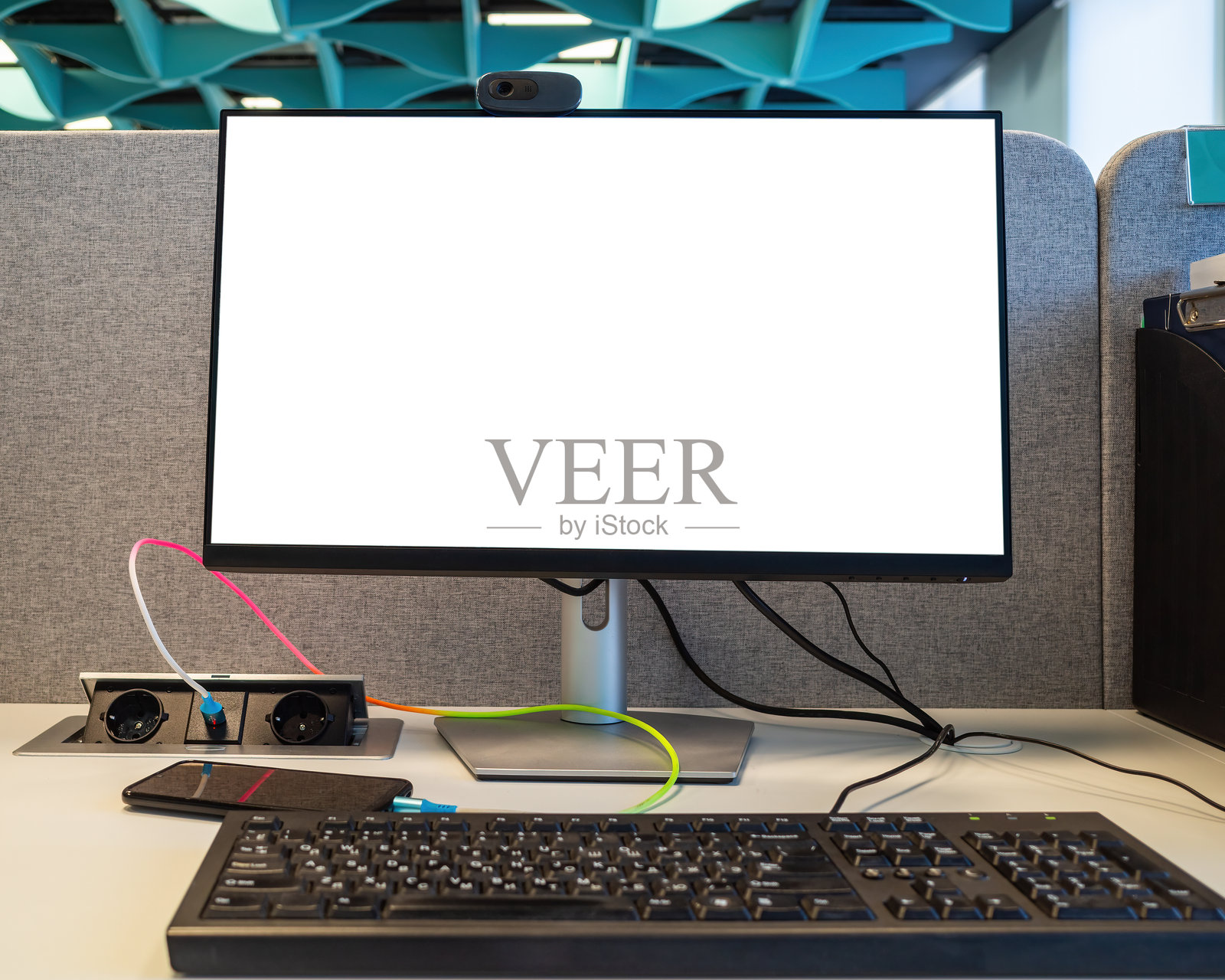 现代办公室房间的桌子上放着一台带有空白白屏的电脑、键盘和智能手机，可用于展示艺术作品或文本的模板，并留有复制空间。照片摄影图片