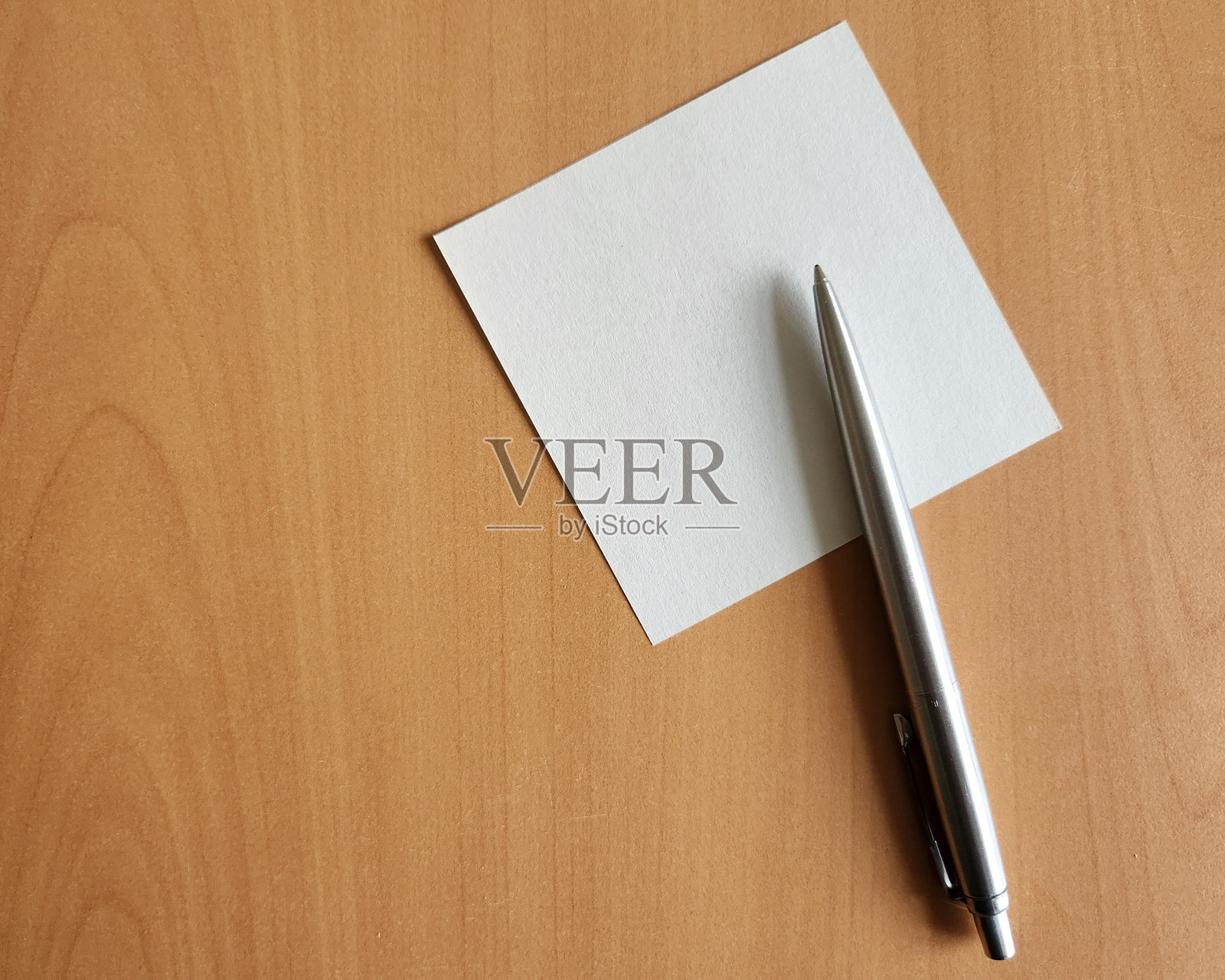 木桌背景上的纸张，用于笔记，配有金属圆珠笔，可用于放置文字信息或多媒体内容。俯视角度拍摄。空白笔记。照片摄影图片