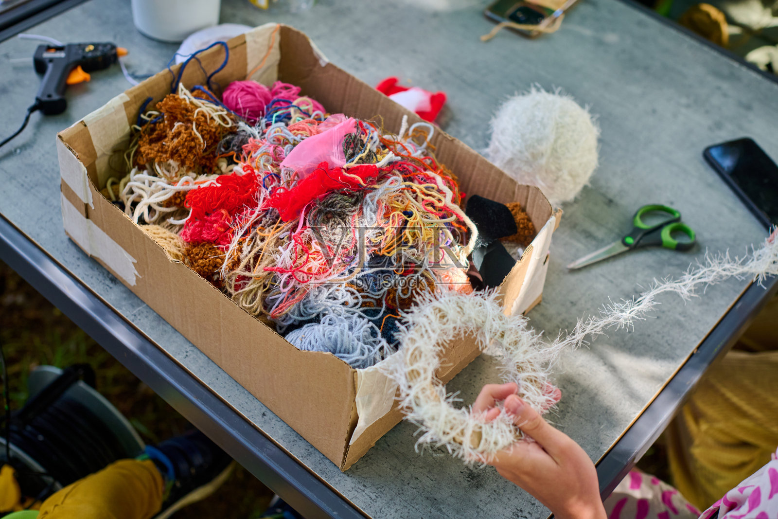 阳光明媚的日子里，孩子们在户外参加毛线编织手工艺工作坊照片摄影图片