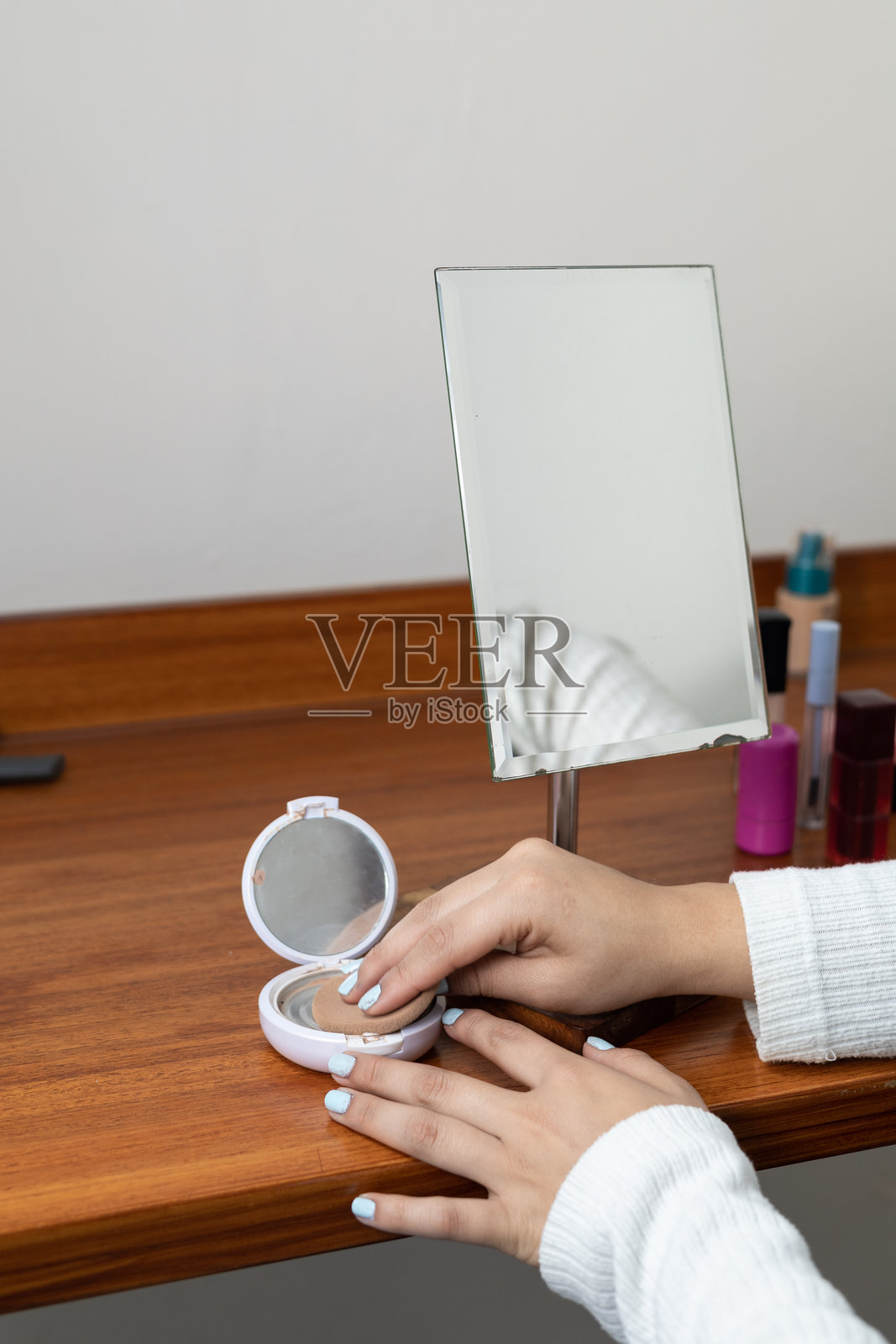 女子在梳妆台前使用散粉，梳妆台配有镜子照片摄影图片