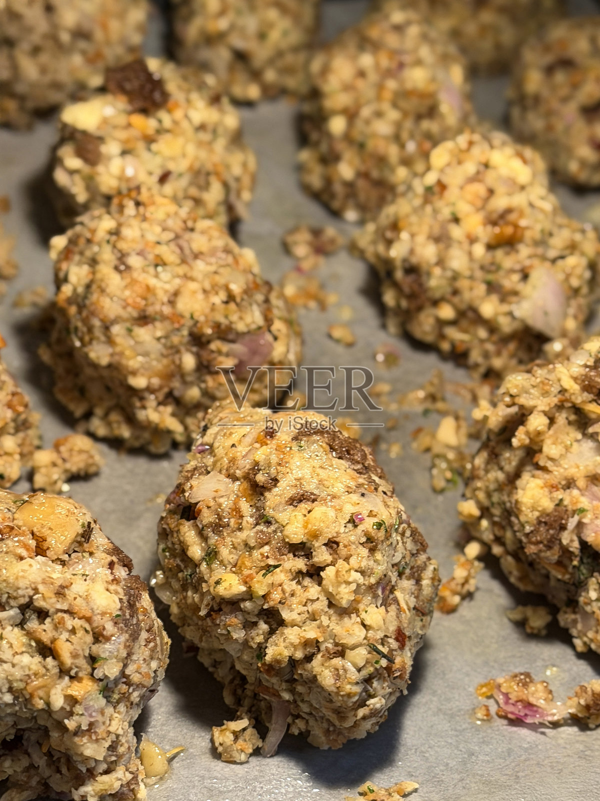 烤箱烤盘中铺有烘焙纸的烤面包馅球的完整画幅图像，鼠尾草和洋葱面包屑馅食谱，俯视角度，聚焦前景照片摄影图片