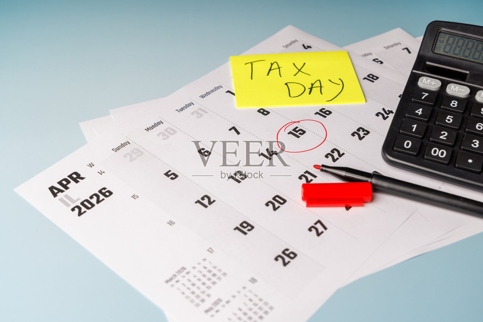 办公桌日历上用红色标记的美国报税日4月15日截止日期，旁边有办公文具和计算器，用于商业报税广告。照片摄影图片