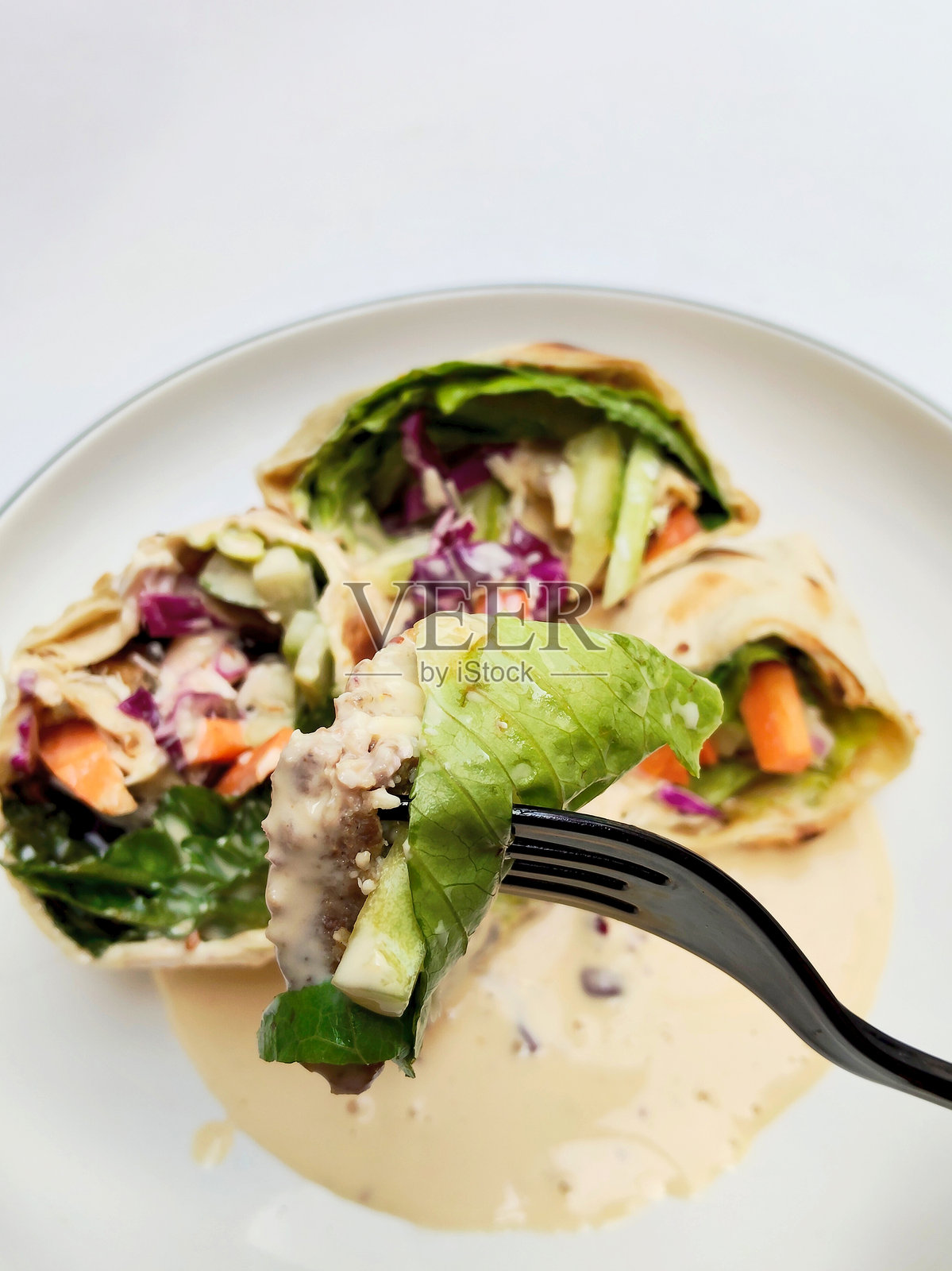 叉子上放着美味切片卷饼，配有新鲜沙拉和奶油酱照片摄影图片