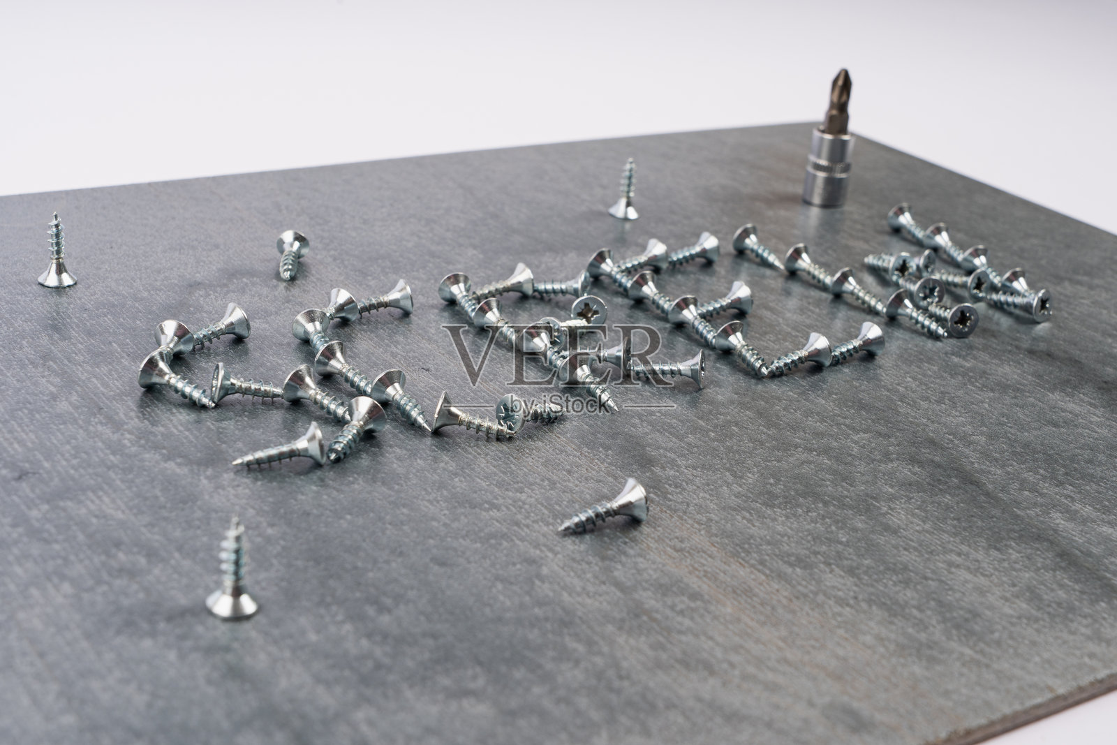 散落在灰色木板上的金属螺丝和螺丝刀照片摄影图片