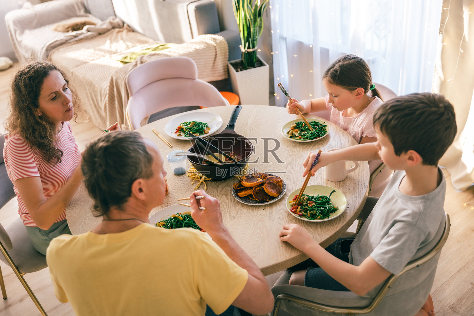 一家人在家烹饪后，在餐桌旁一起吃绿色面条照片摄影图片