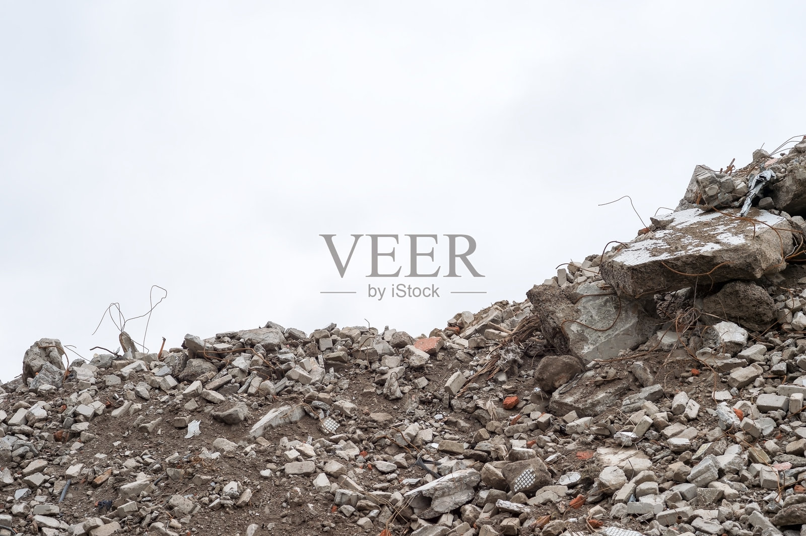 阴天下的废墟和暴露着钢筋的碎裂混凝土瓦砾，预留复制空间，象征破坏与衰败的概念照片摄影图片