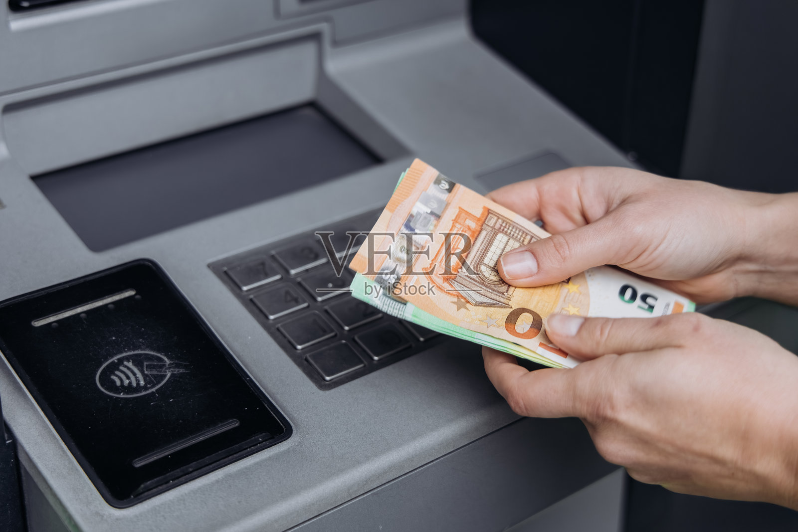 手持多张欧元纸币使用自动取款机照片摄影图片